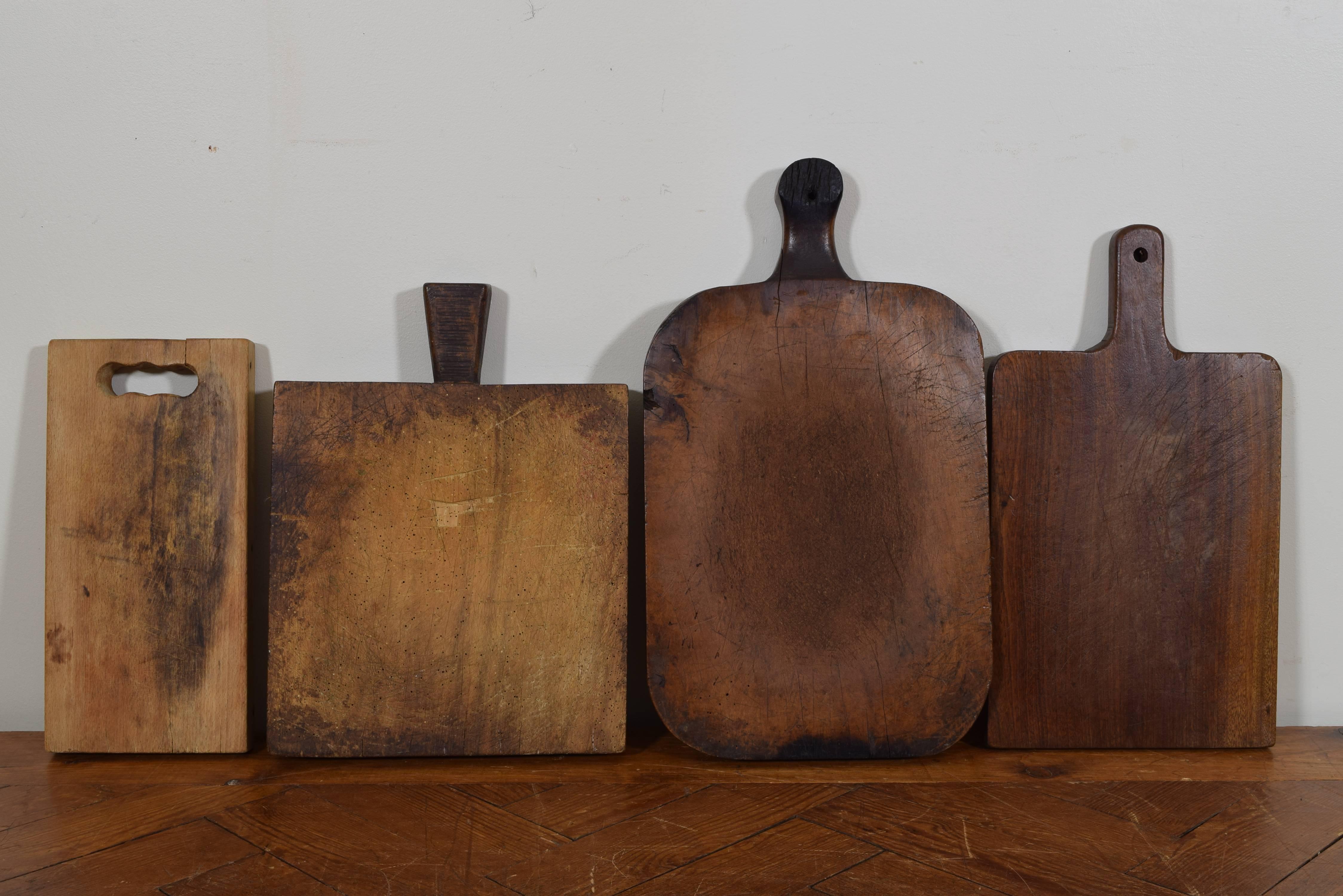 Group of four French cutting boards of varying shapes and sizes and having wear patterns, the largest measuring 21.5