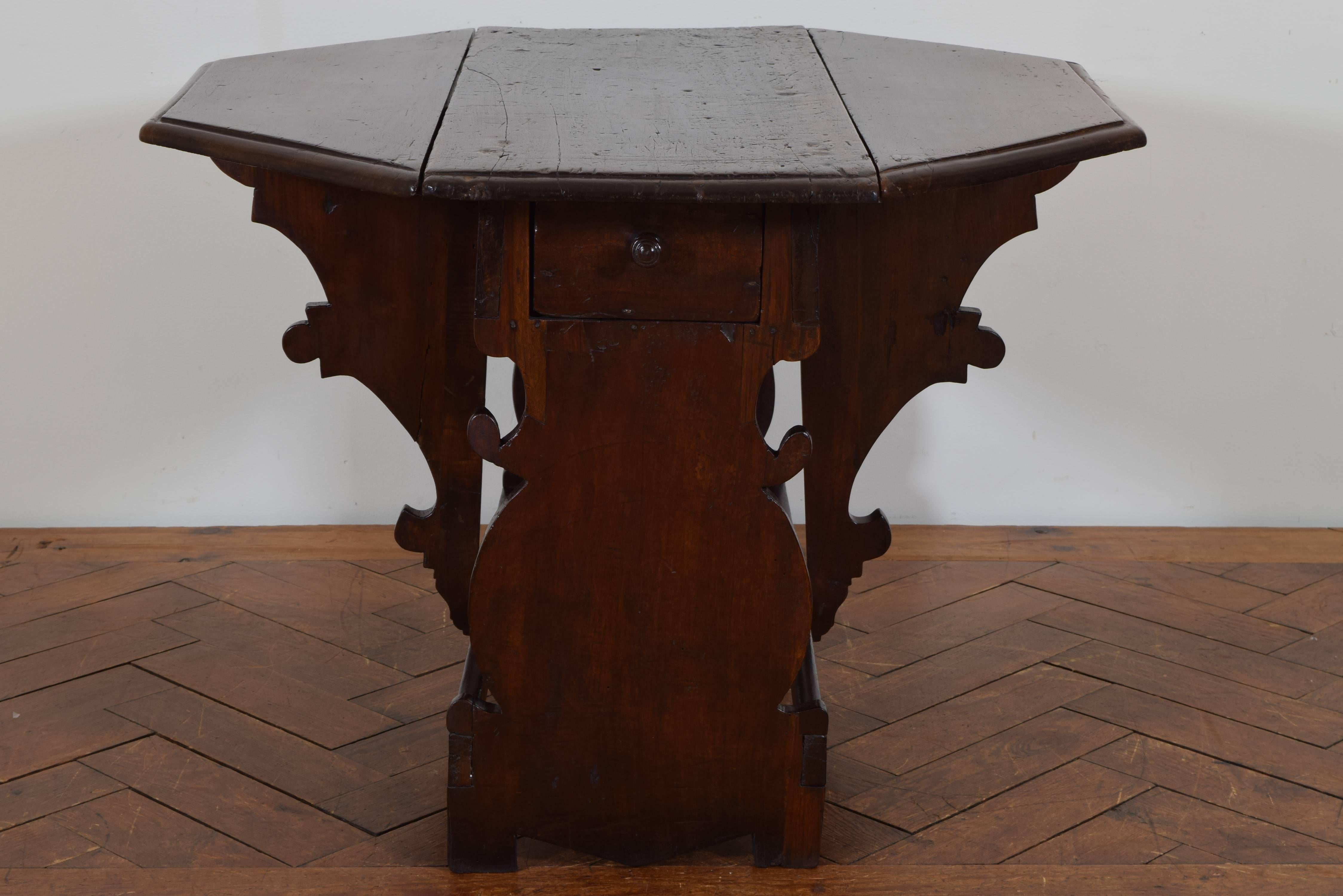 The top, when opened, of octagonal form and having a molded edge, the sides of shaped walnut, joined by horizontal stretchers and a case housing one long drawer, middle section measuring 38.5 inches by 15 inches.