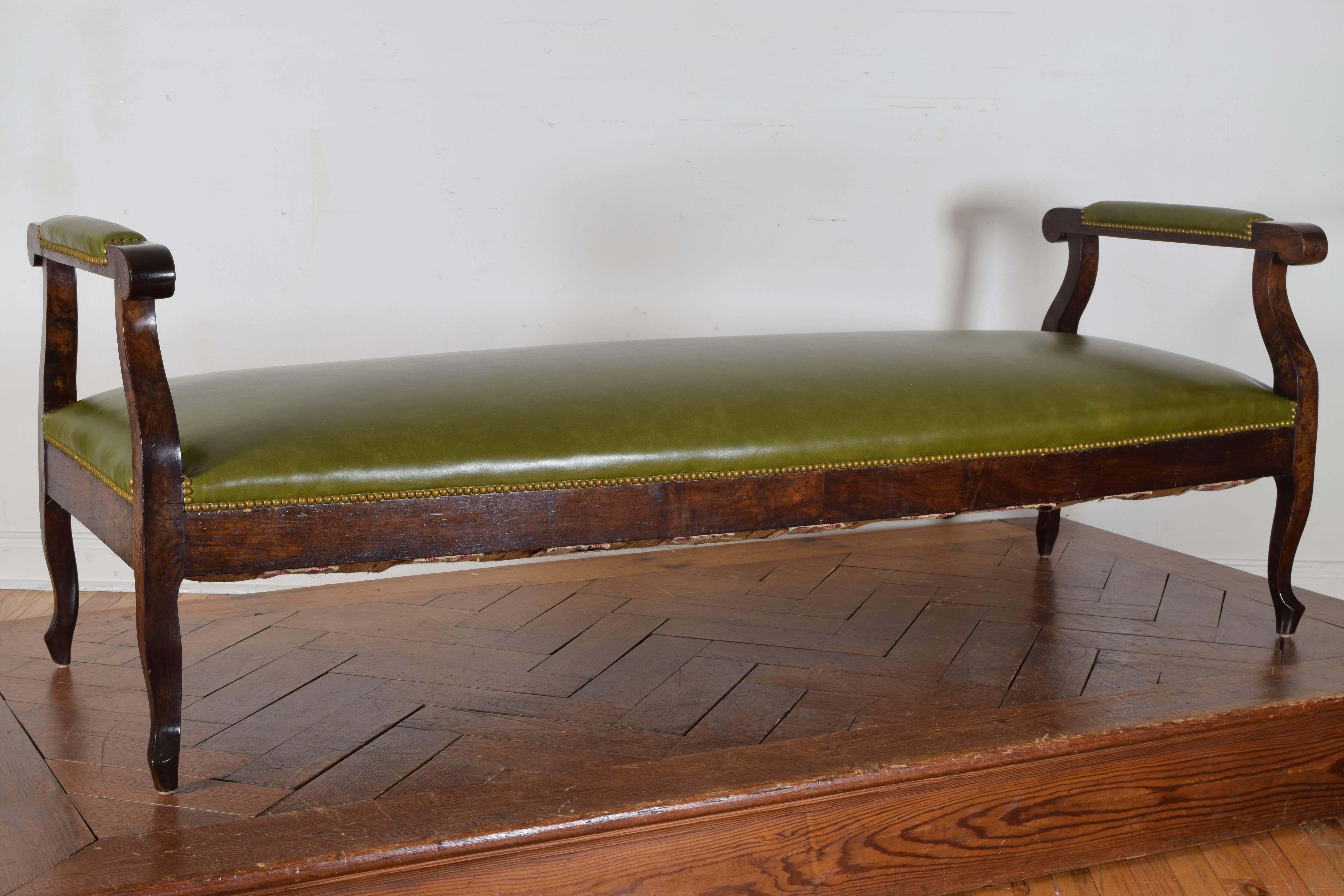 The rectangular bench having raised arms and upholstered in green leather trimmed in patinated brass nailheads, the legs are of cabriole form.