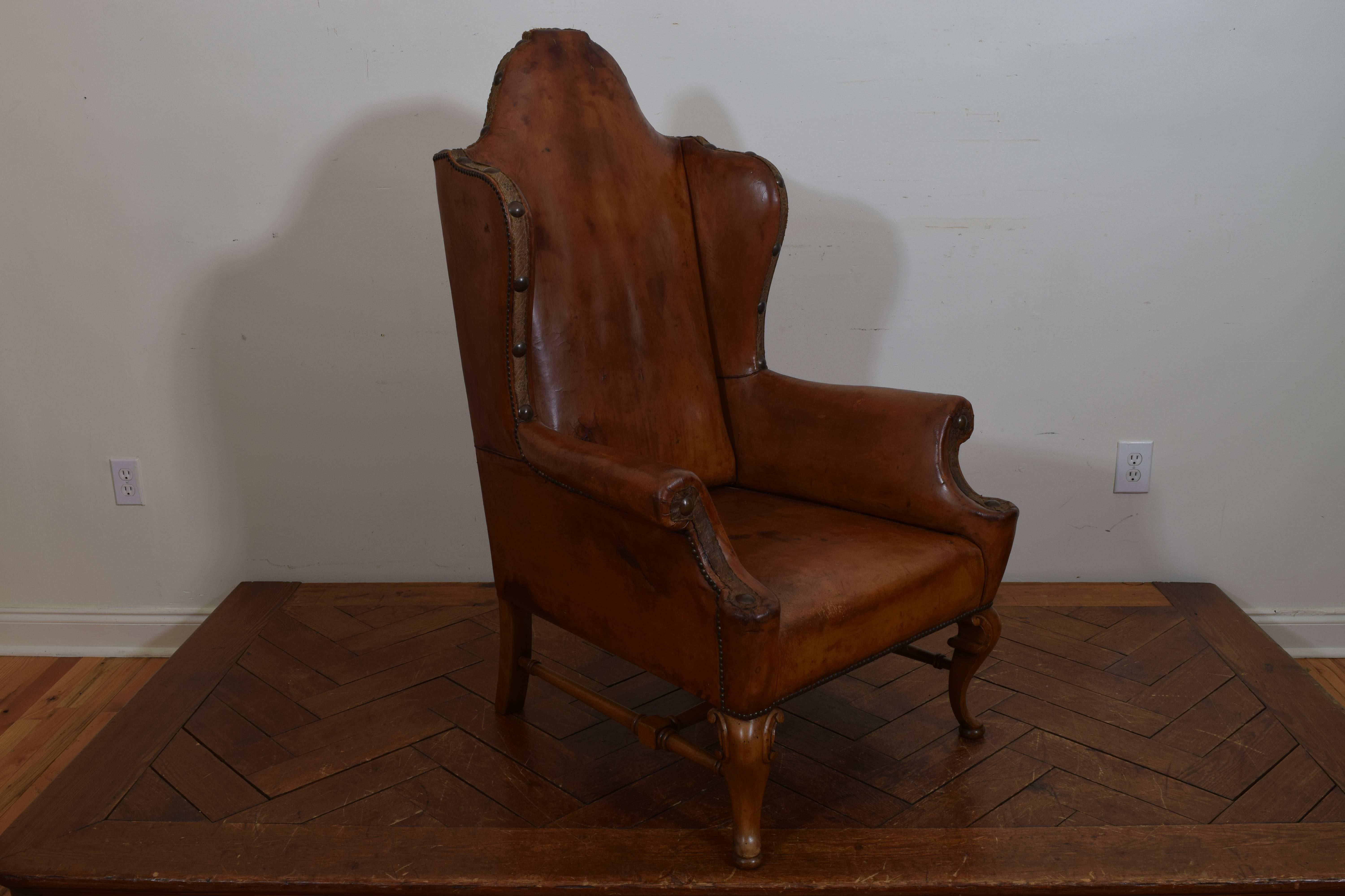 Having a shaped backrest and flared arms with a generous seat, trimmed in silk tape and having large brass nailheads, carved legs and feet in light walnut.