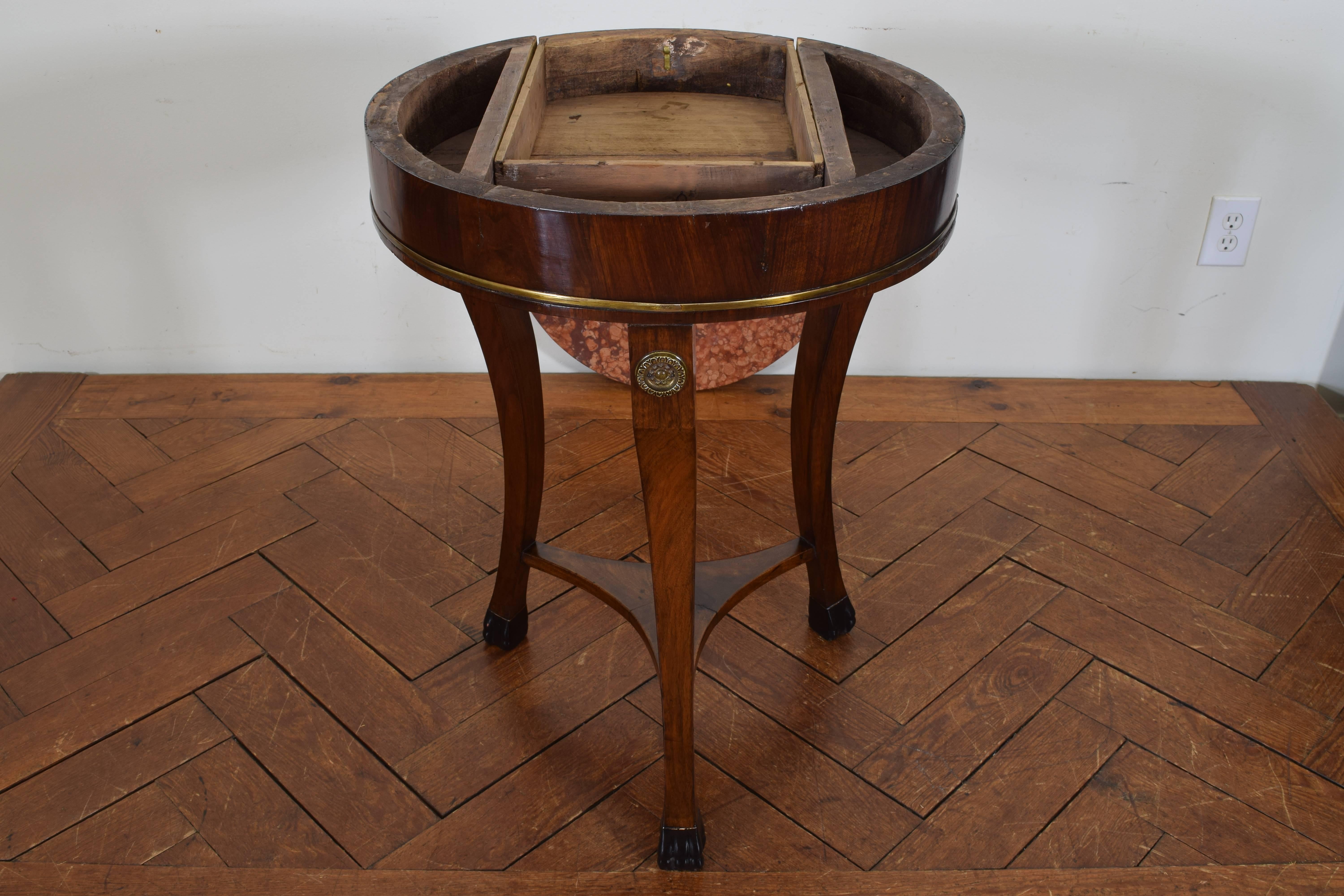 Having a round marble top resting on a conforming case housing on drawer and having a lower brass banded edge, the shaped legs with applied brass rosettes and connected by a shelf stretcher, terminating in ebonized animal feet.