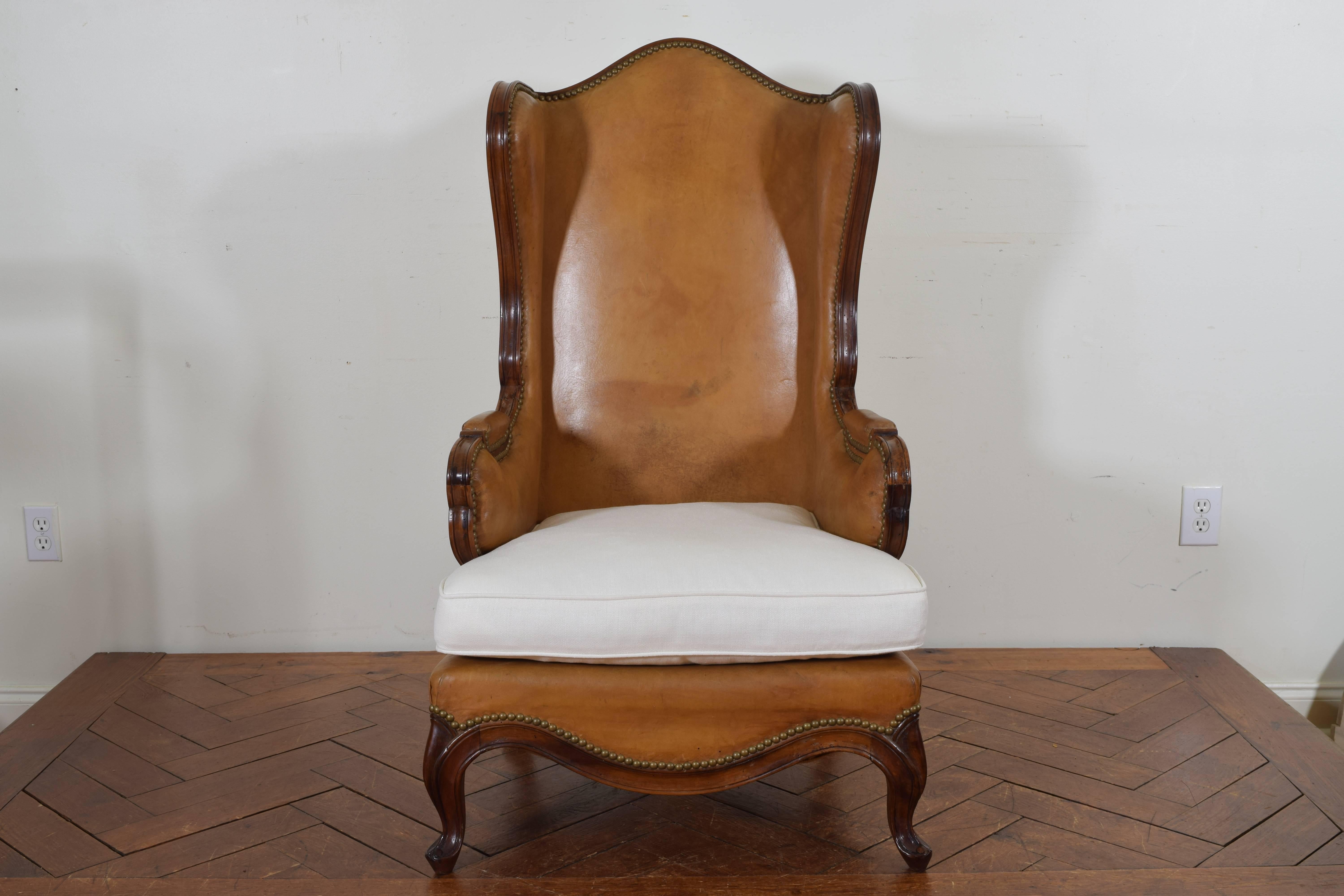 Spanish Rococo style walnut, leather, and linen upholstered bergère with a loose down filled cushion seat.