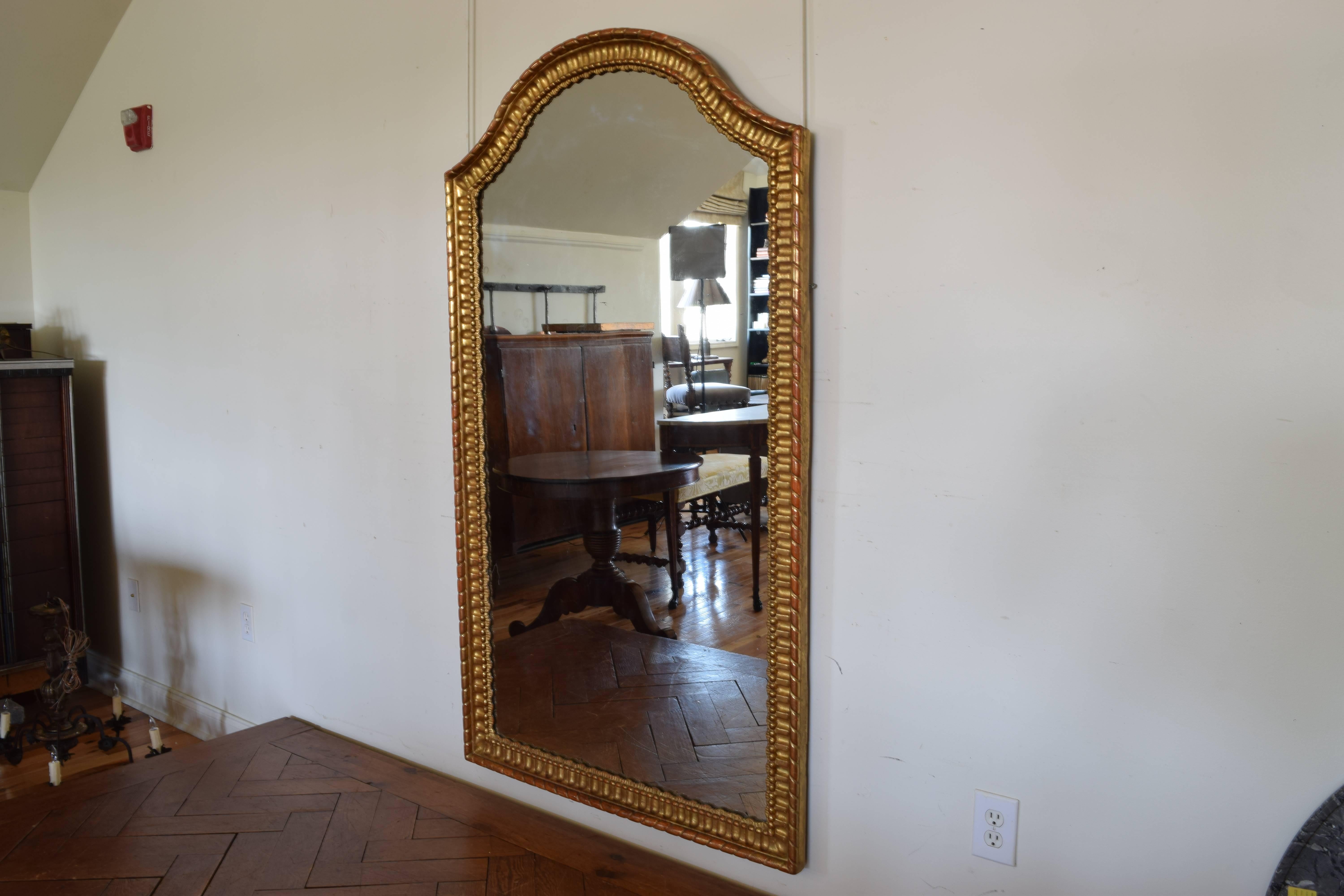 Italian rococo style tall carved giltwood mirror of rectangular form with an arched top, the molding carved and having bead molding.