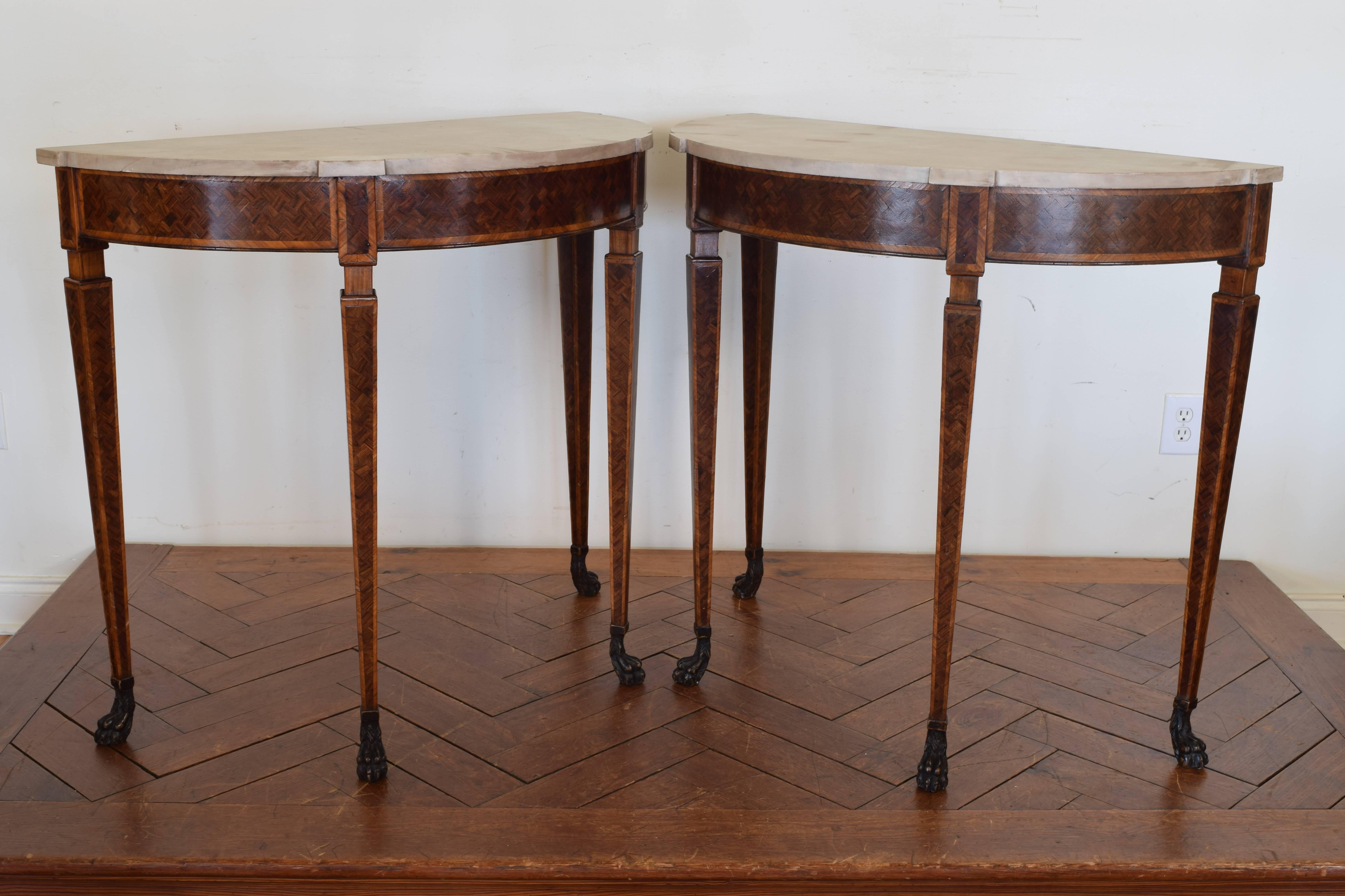 Pair of demilune form and having marble tops with notches above front legs, covered in walnut veneers, square tapering legs resting on ebonized paw feet, 19th century.