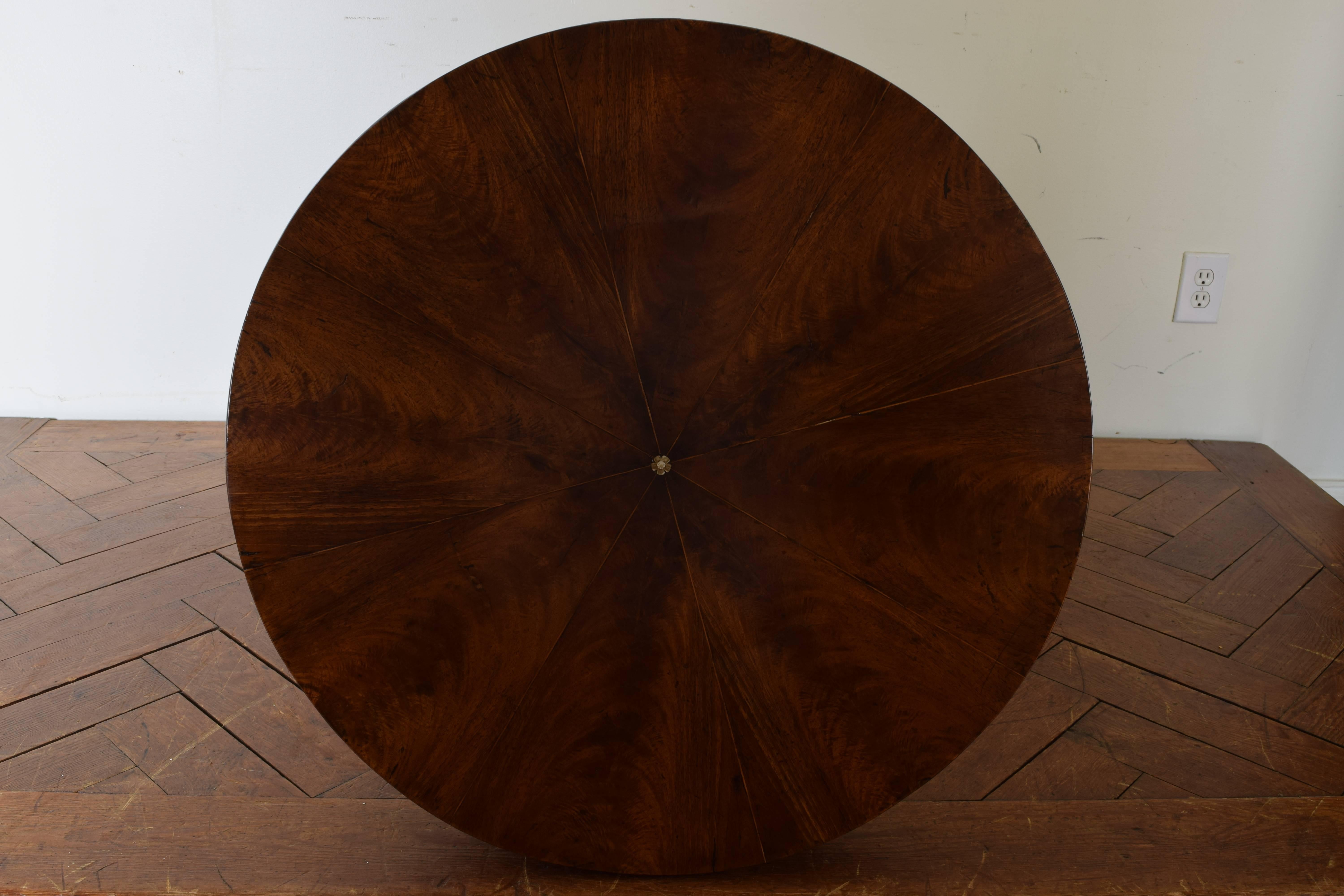 Center table having a round top with thin radial inlay and a centered rosette of mother-of-pearl, the apron slightly convex, the columnar support with quatrefoils, arches and spiral carved corners, raised on a shaped tripartite base and curled feet.