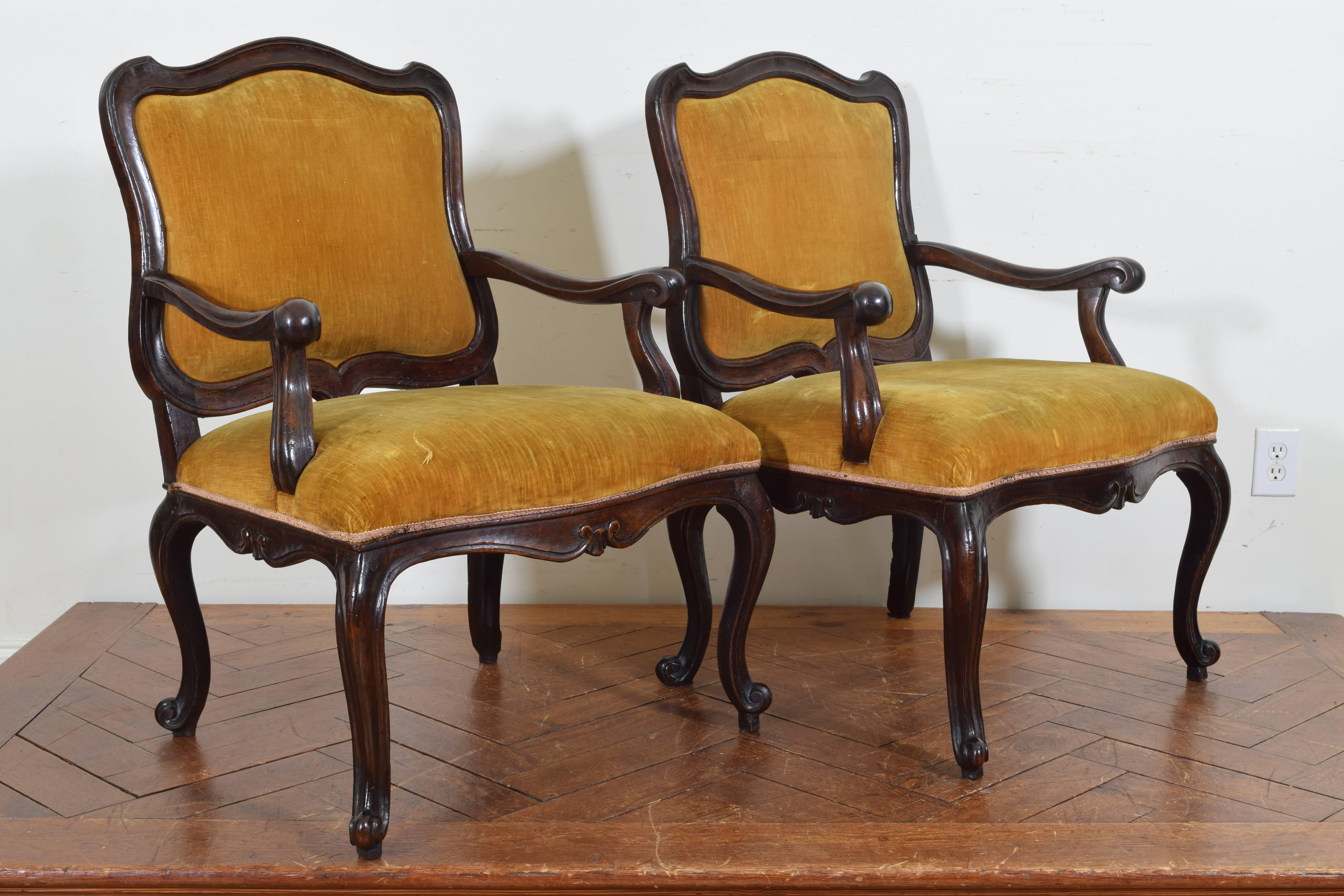 Each chair with a shaped backrest and a removable upholstered section, the carved arms and arm supports flank generous fitted seats with carved aprons, raised on shaped cabriole legs.