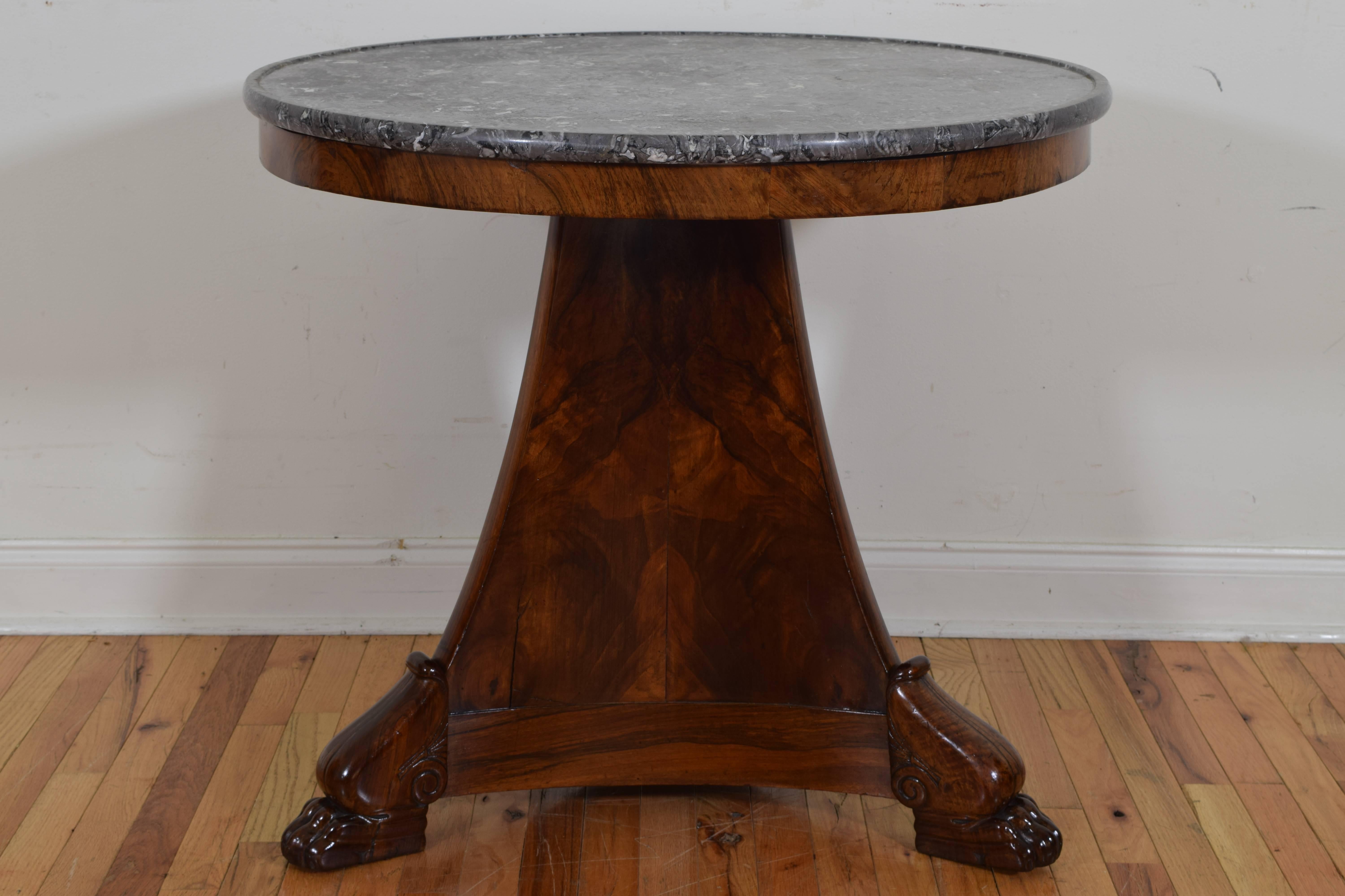 Having a grey and white circular marble top with raised edge, the walnut veneered table of tripartite form and raised on shaped and carved feet.