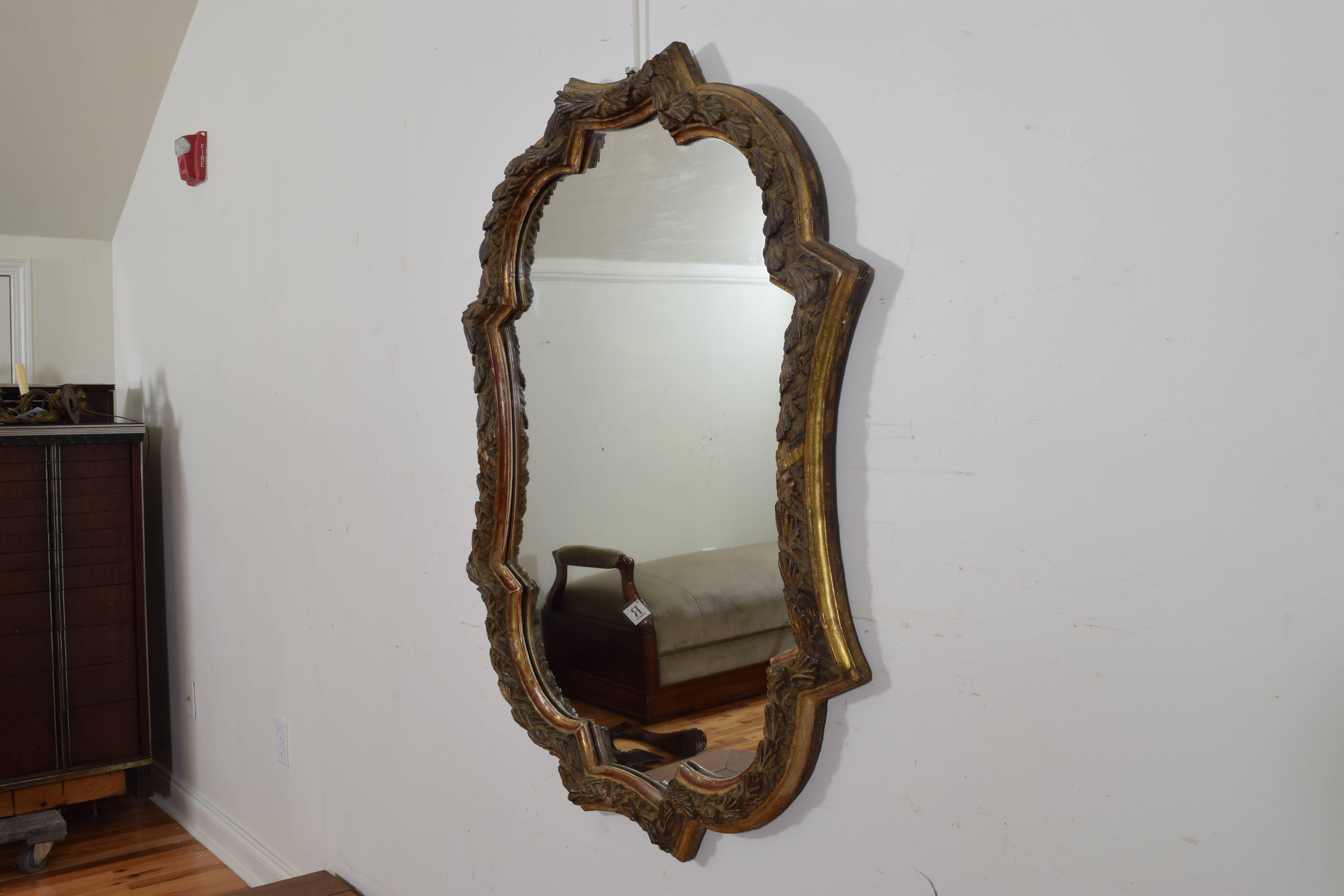 The shaped frame constructed of carved and gilded wood, with a lower molded edge.