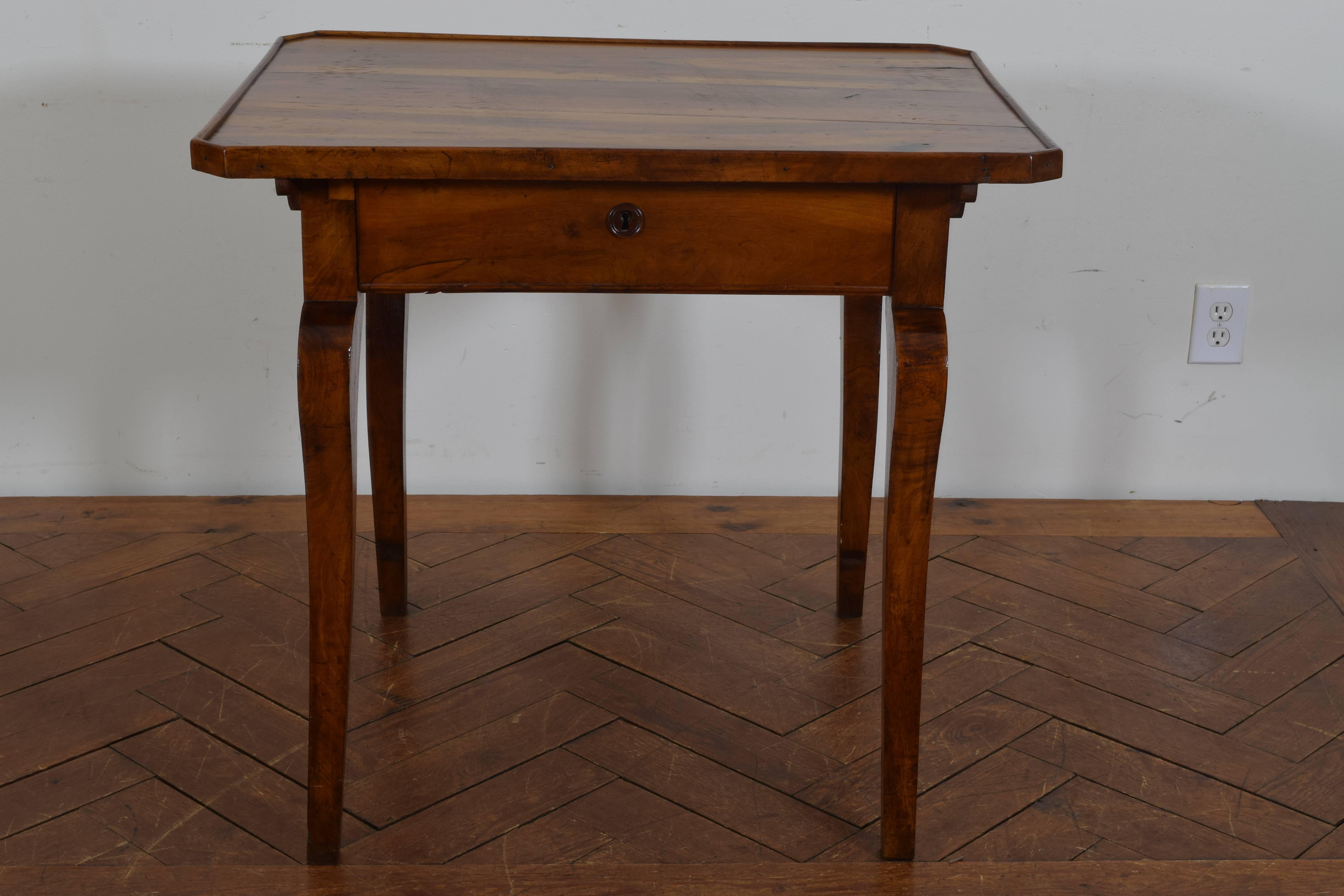 Having a top with canted corners and beautiful grain pattern, with one drawer, raised on interestingly shaped legs.