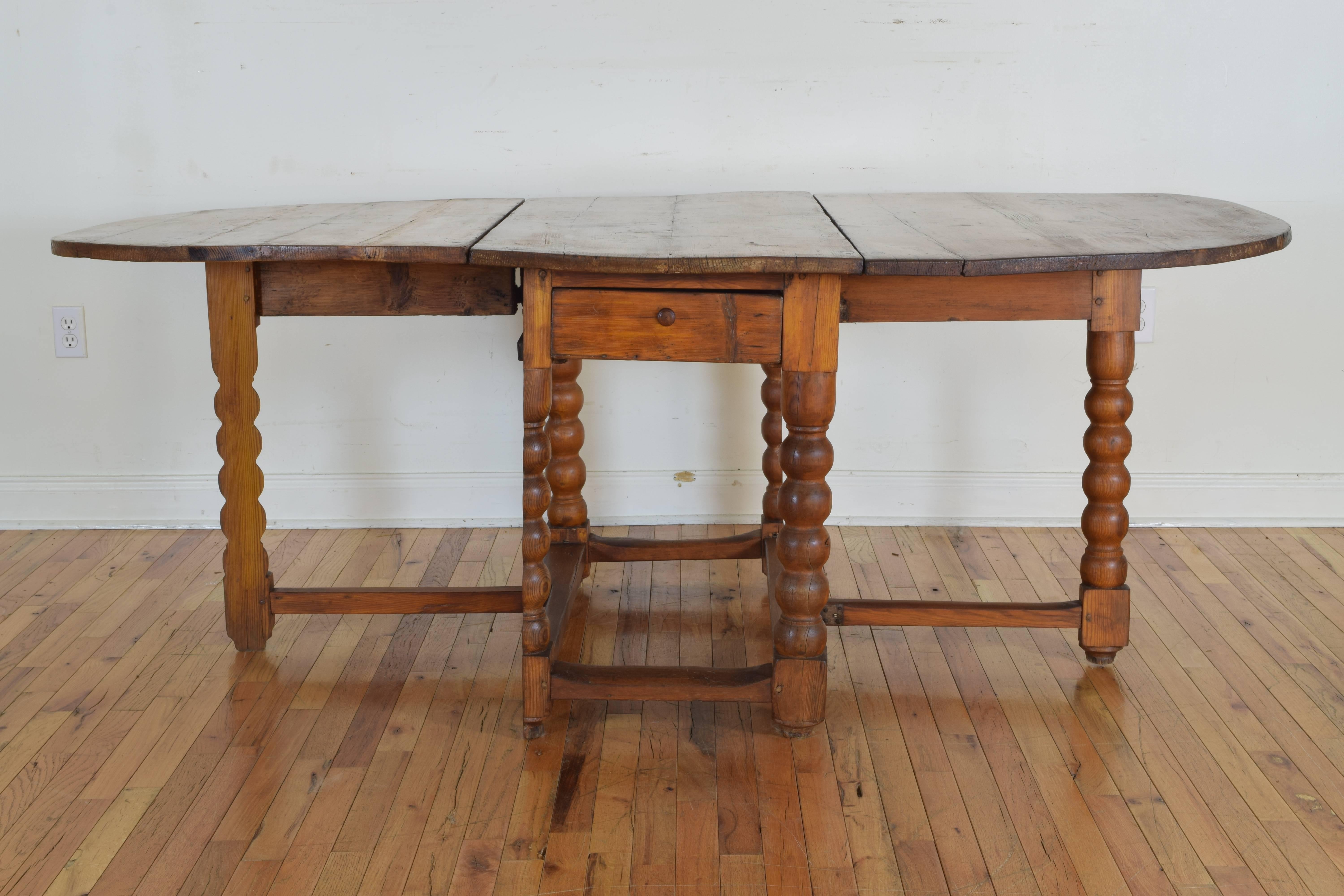 Having two large demilune shaped halves straddling a center section housing one-drawer, the whole raised on bobbin turned legs joined by a rectangular stretcher, central portion measures 46.75" by 21.5".