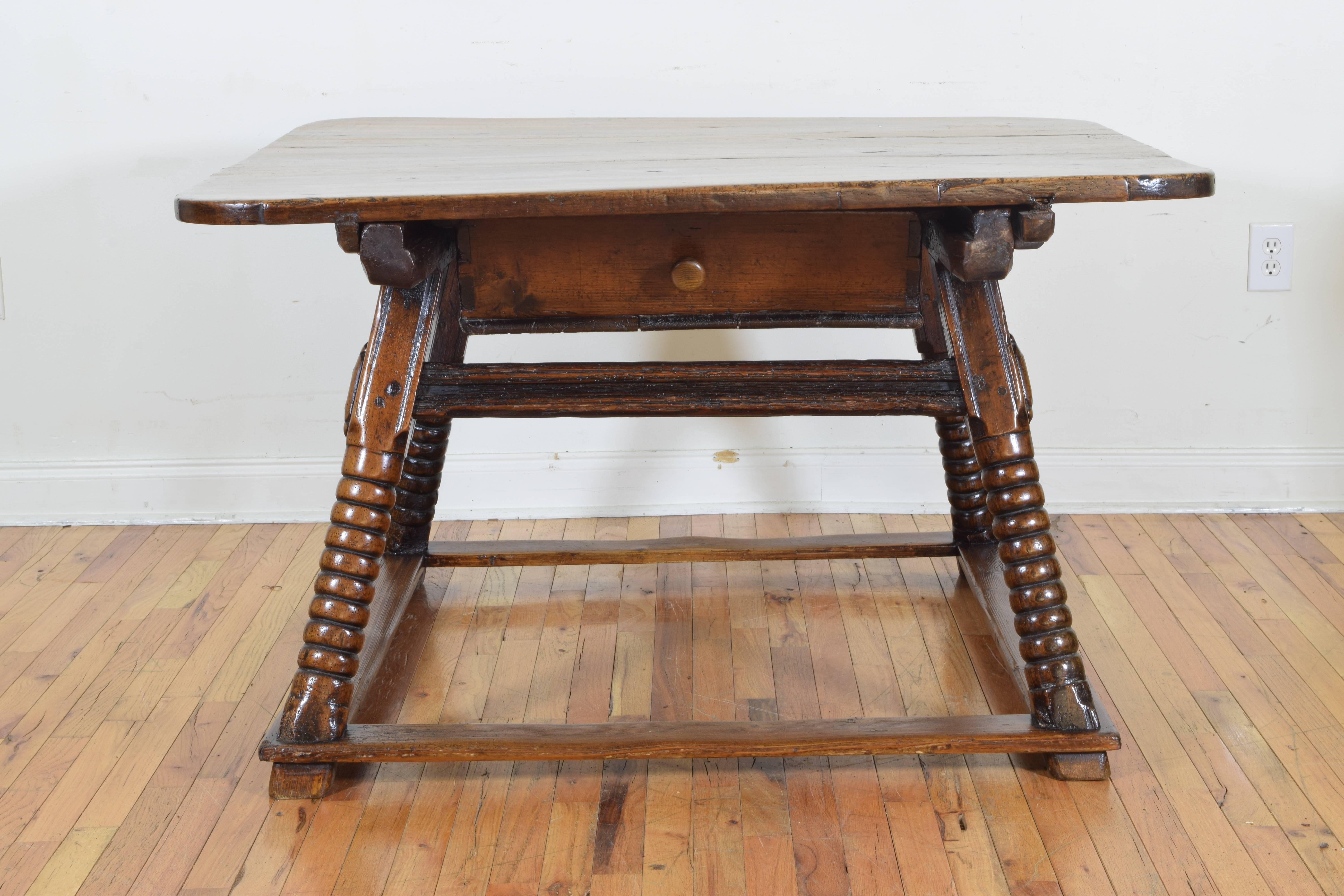 the square top with rounded edge above a frame housing one drawer and raised on splayed and turned legs, the legs joined by a flattened square stretcher and raised on small feet. 18th Century