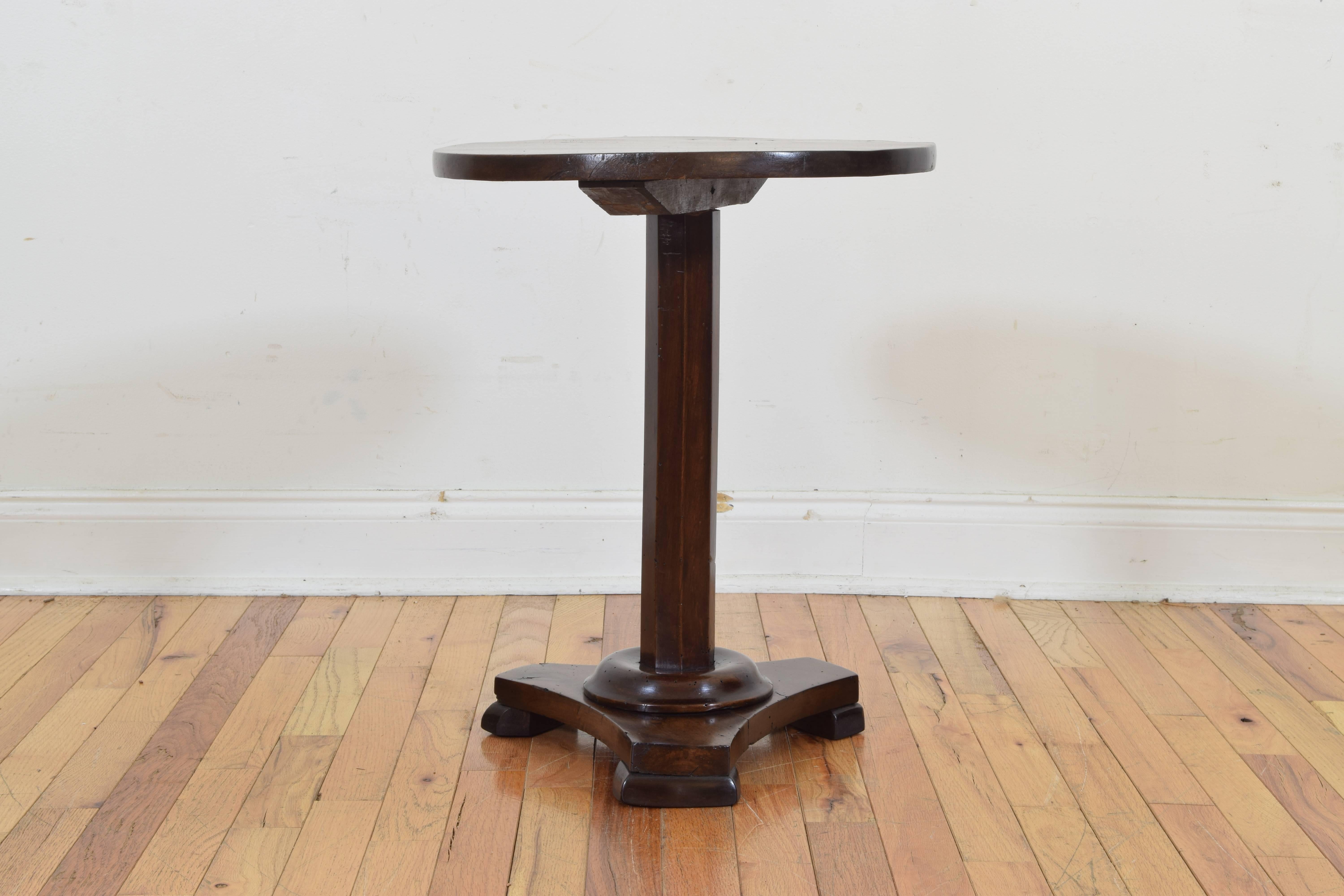 Reduced in height to cocktail table size, having a round top atop an octagonal column raised atop a tripartite base with small rounded square feet.