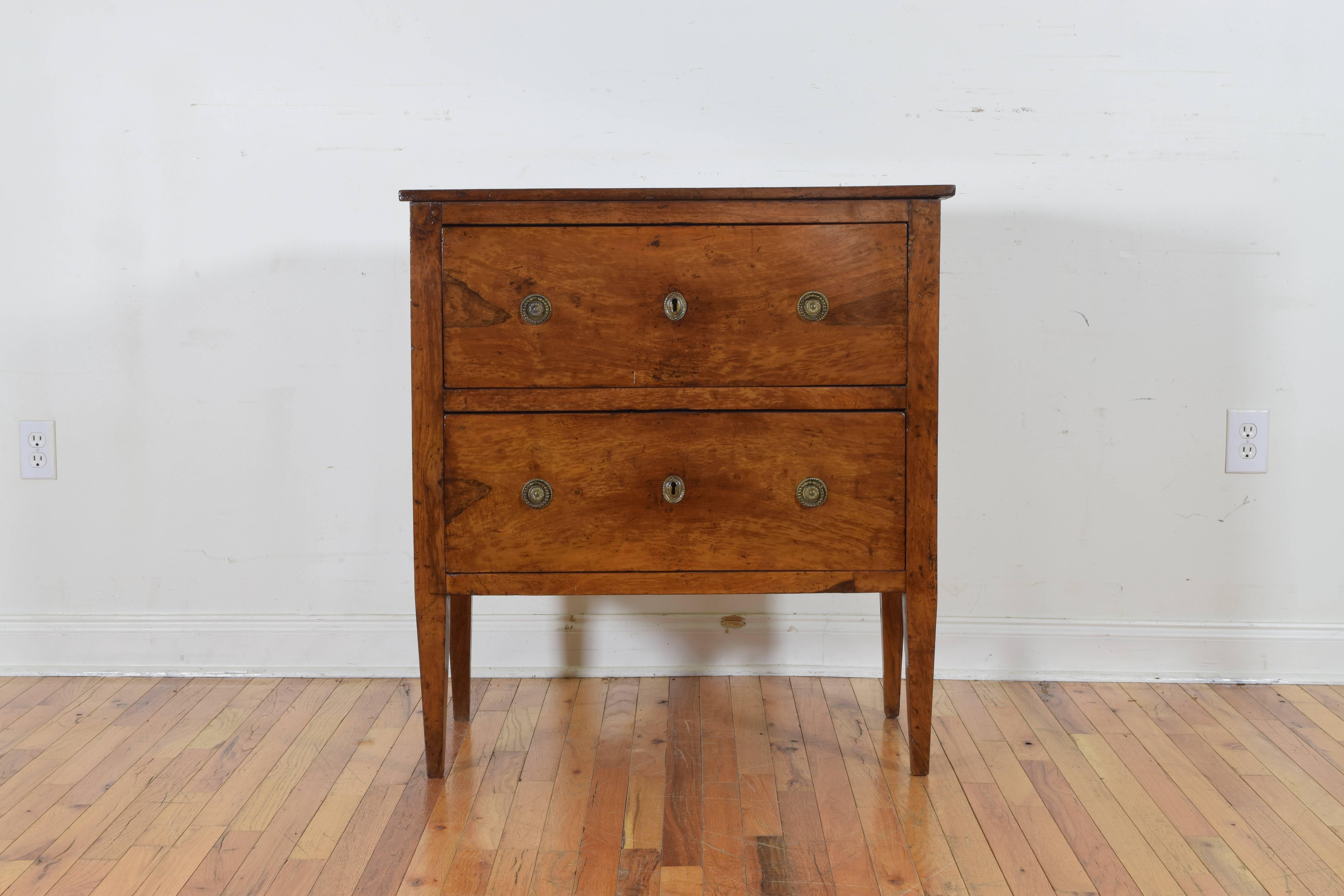 having a rectangular top above a conforming case housing two drawers, the side panels of the commode are trimmed in brass, retaining antique hardware, raised on a square tapering leg
early 19th century
