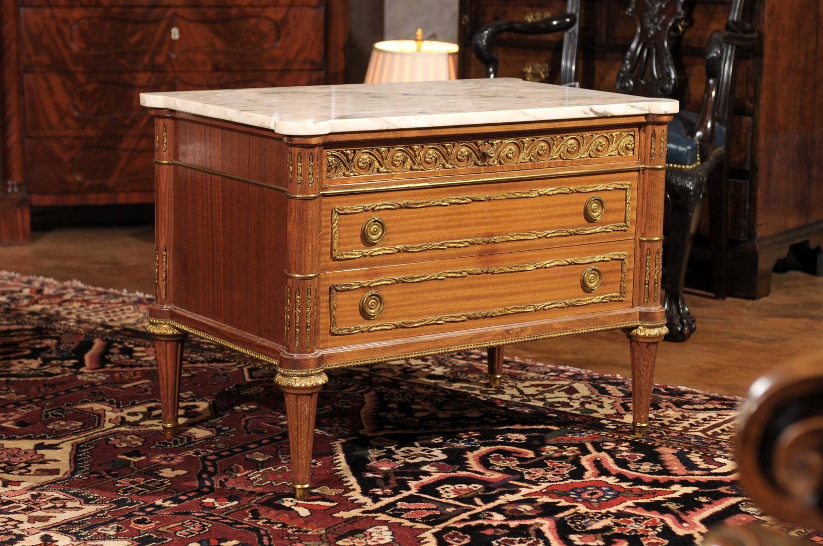 This is a beautiful Louis XVI style petite commode, vintage 1930s. The detailed work of the bronze ormolu is gorgeous. The top drawer is not as deep as the other two drawers and the bronze swirls like waves move completely across the facade this