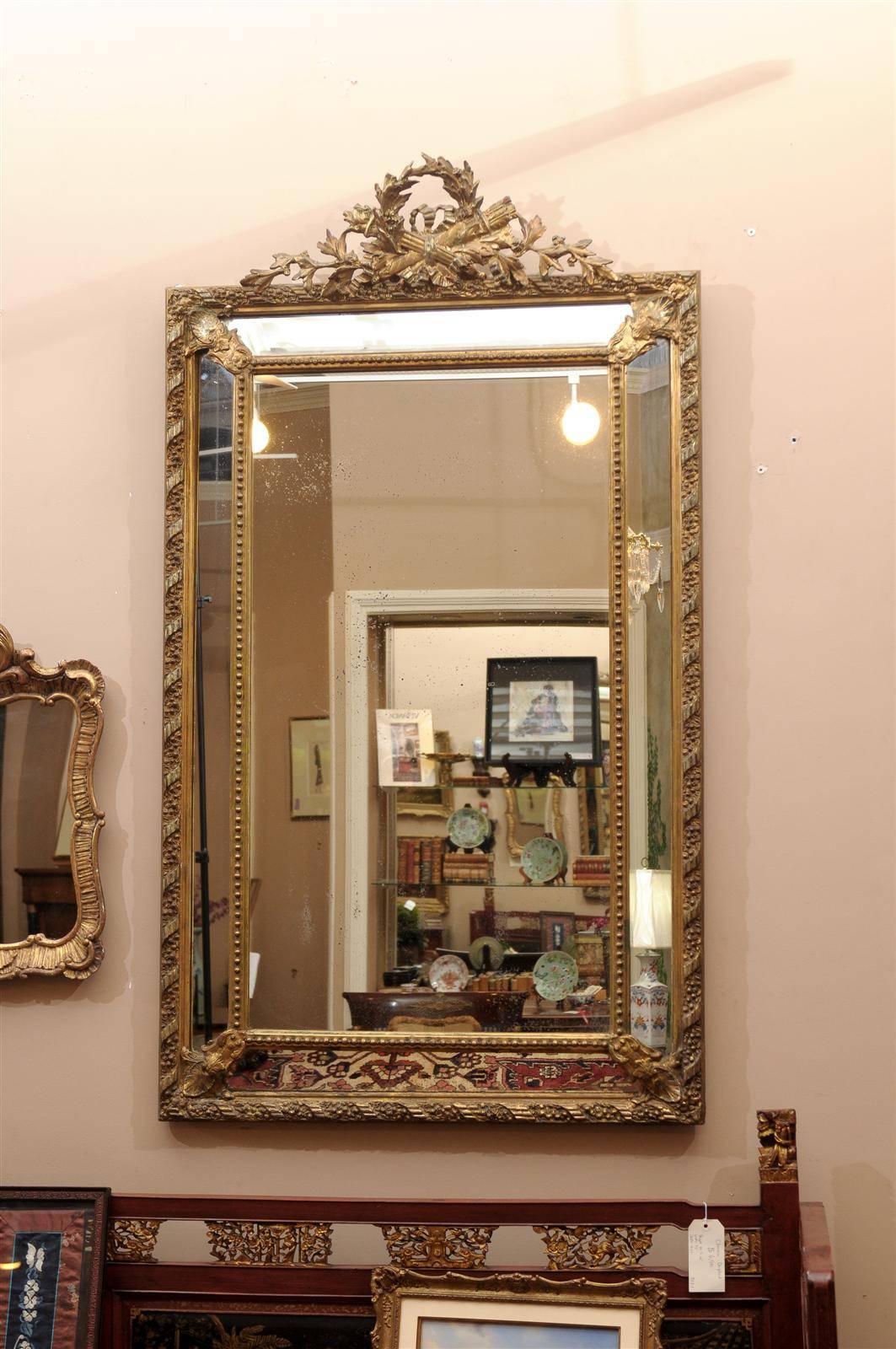 Mid-19th century hand-carved giltwood cushion mirror. Torch, quill and wreath pediment above the molded rectangular frame. The original glass has aged beautifully.