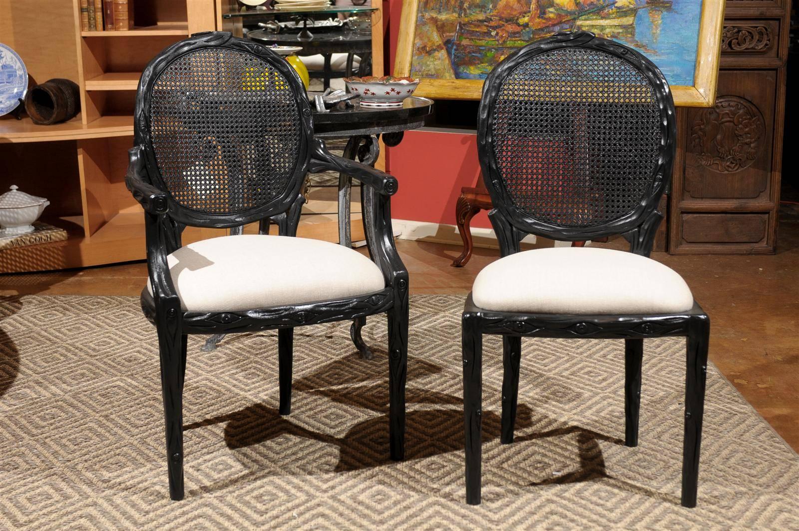 A nice set of cane back chairs carved front and back painted black with a natural linen newly upholstered seat. Two armchairs and four side chairs. 