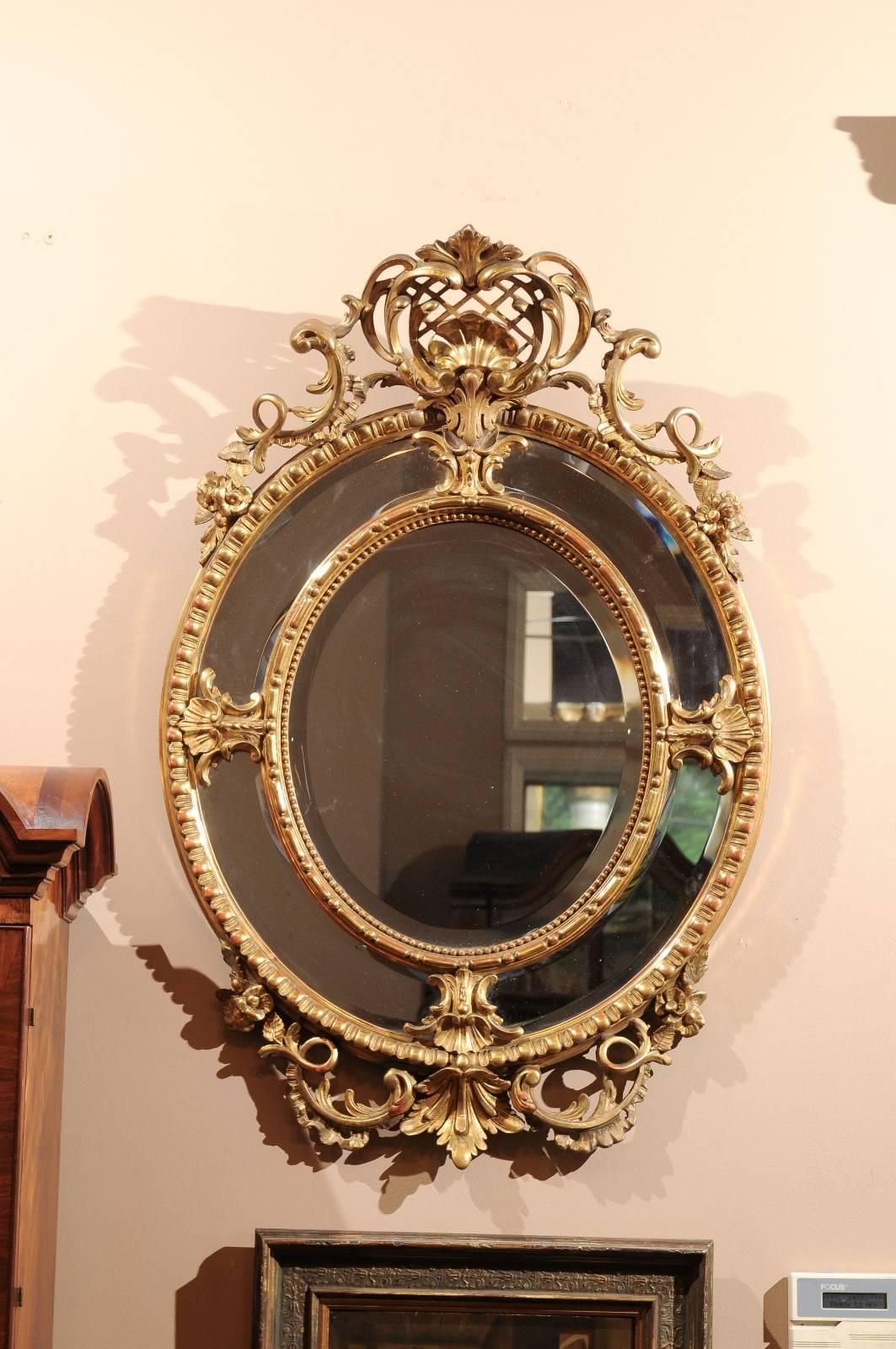 An exquisite circa 1840s gold leaf, ornately carved oval mirror. Hand bevelled and original mercury glass. The crown tips forward. A gorgeous addition to any room.