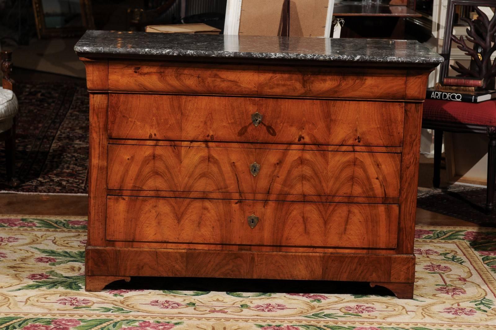 A large bookmatched burled walnut French Louis Philippe commode with a marble top. Three drawers with brass escutcheons for key entry. The wood is gorgeous and would be a statement in any room.