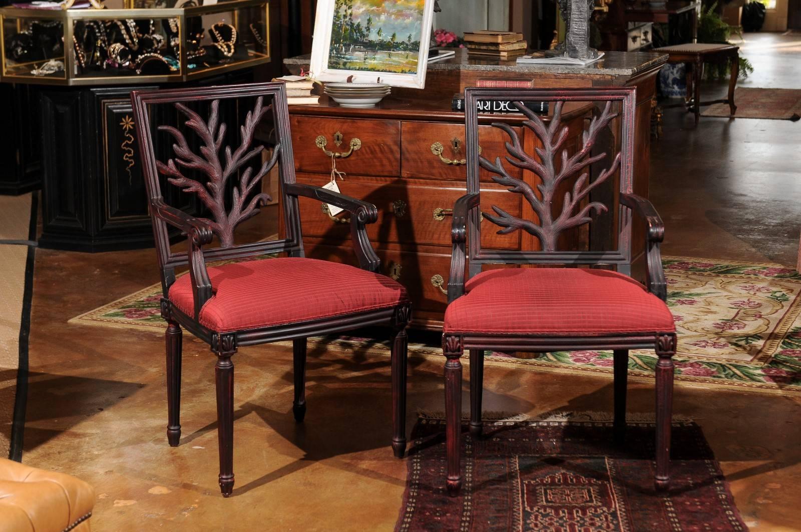 A unique pair of side chairs with a tree branch design. The chair has a slight red undertone on it.