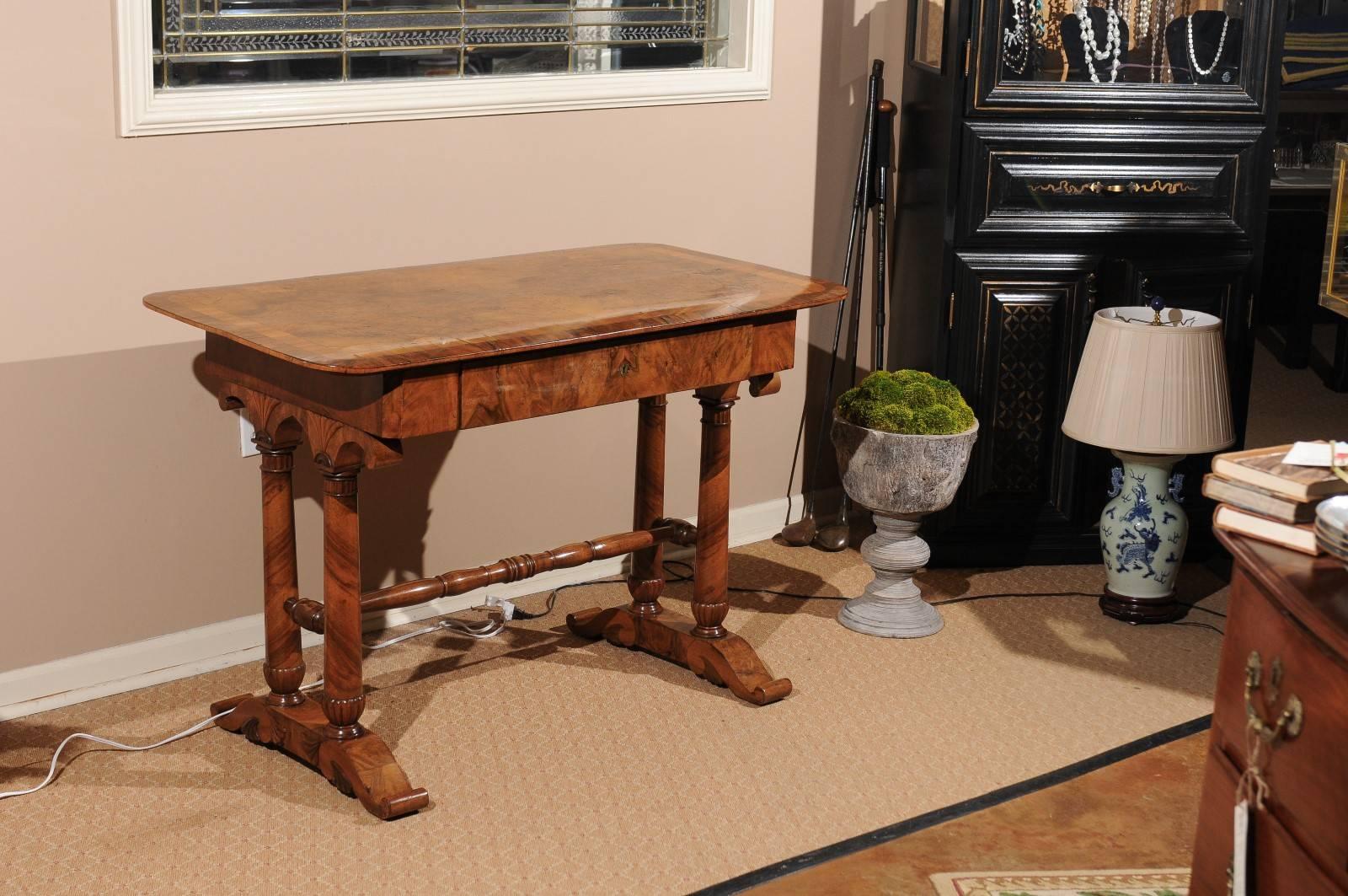 A beautiful circa 1830s writing table with crossbanded top, returned column supports and stretcher, scrolling feet.