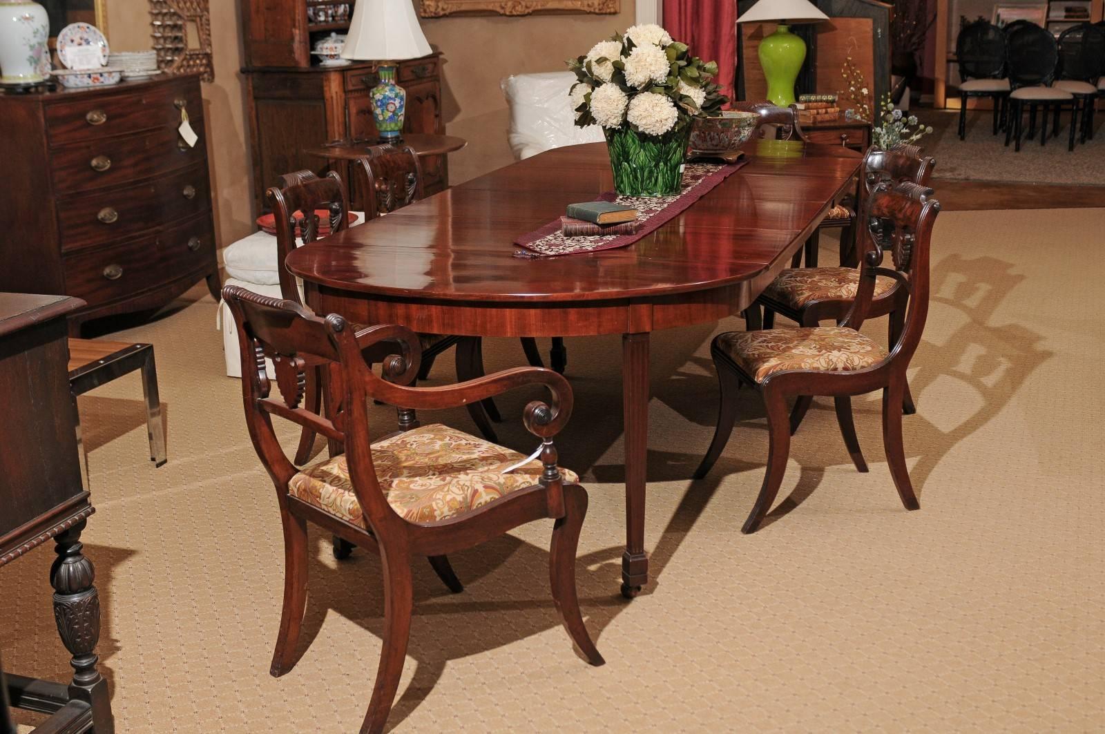 A beautiful period flame mahogany dining table with four leaves. It is resting on six fluted and tapered legs with block feet and square casters.