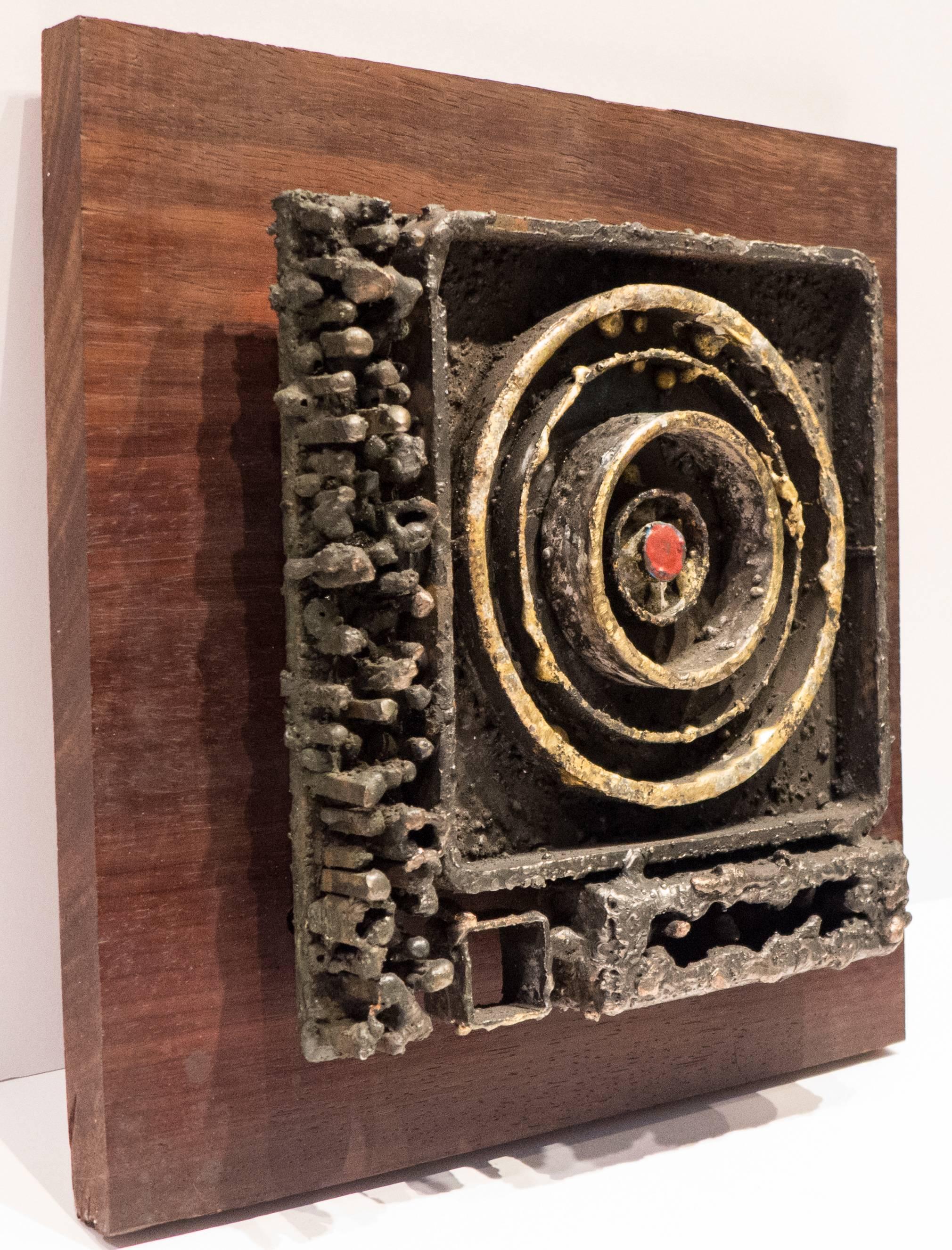 Brutalist abstract relief of blackened steel with fused bronze, copper, and glass enamel. Mounted on a wooden board. Titled 