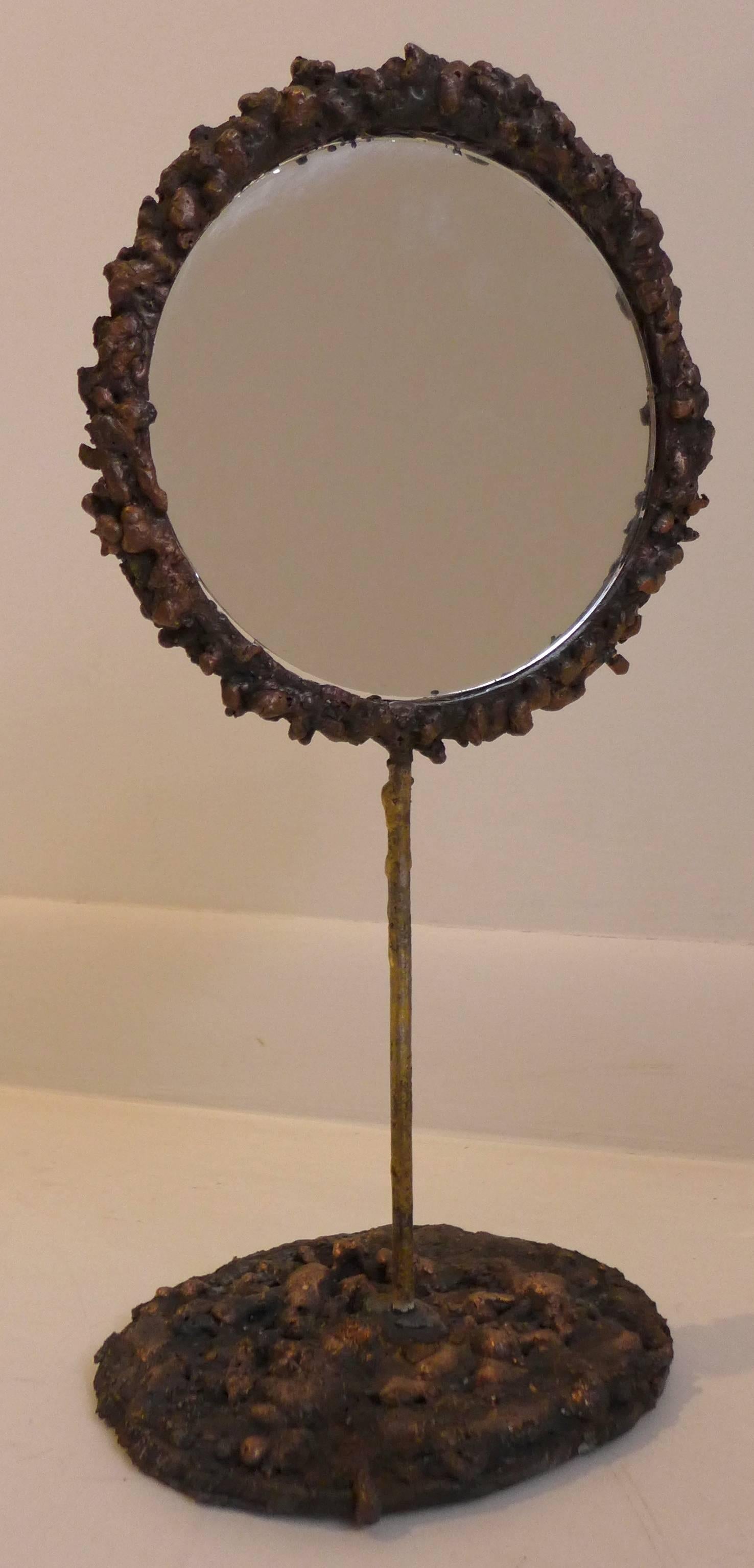 Brutalist double-sided mirror of welded copper by Des Moines, Iowa sculptor James Anthony Bearden. The welded copper ingots form a ring around two pieces of mirrored glass, which are joined via a brass stem to the topographical welded copper base. A