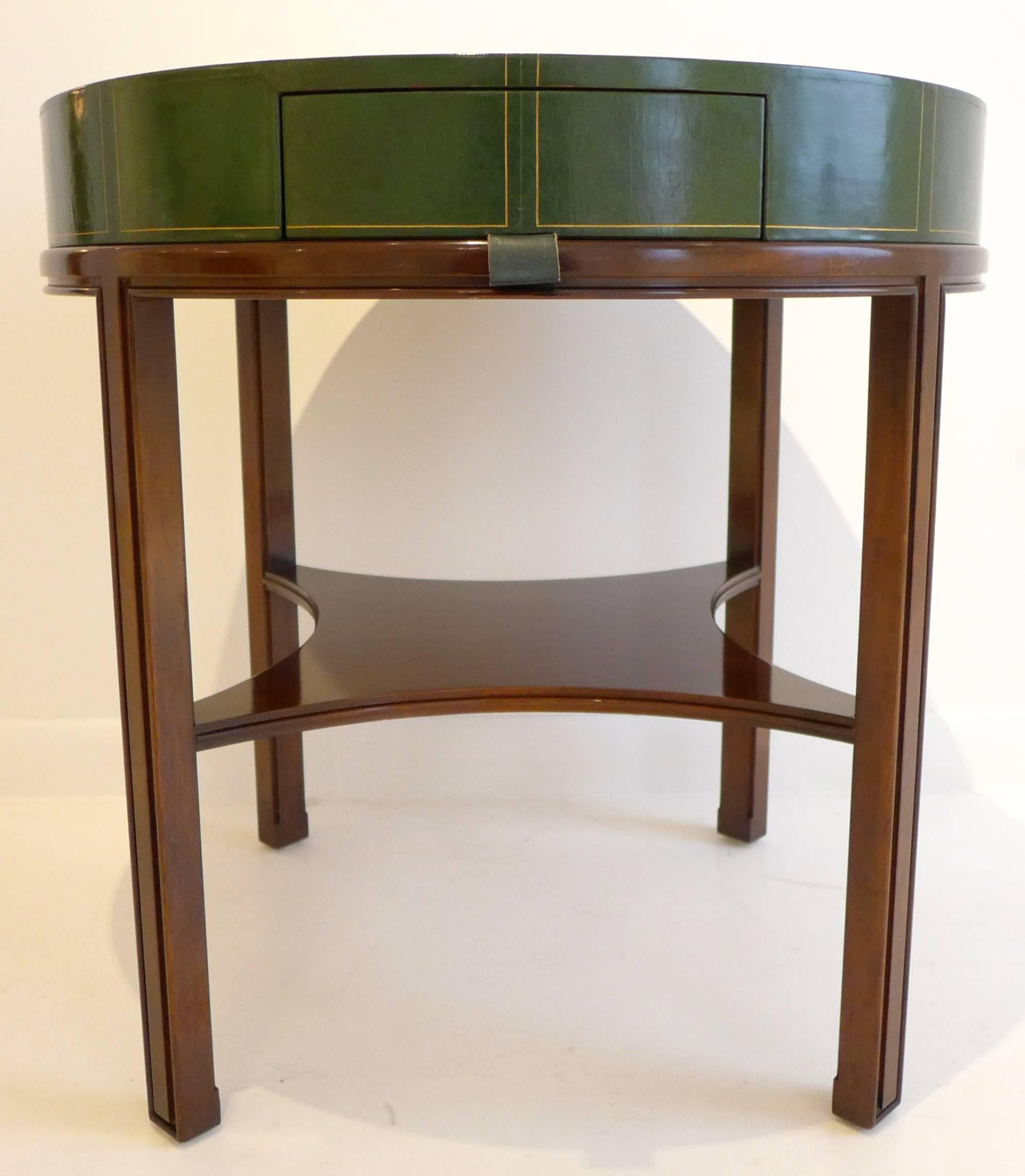 Moderne-style occasional table or game table with channeled mahogany base and green embossed leather top with mahogany center.  With a small drawer with leather pull and tapering medial shelf.  Designed by Tommi Parzinger and produced by Charak, c.