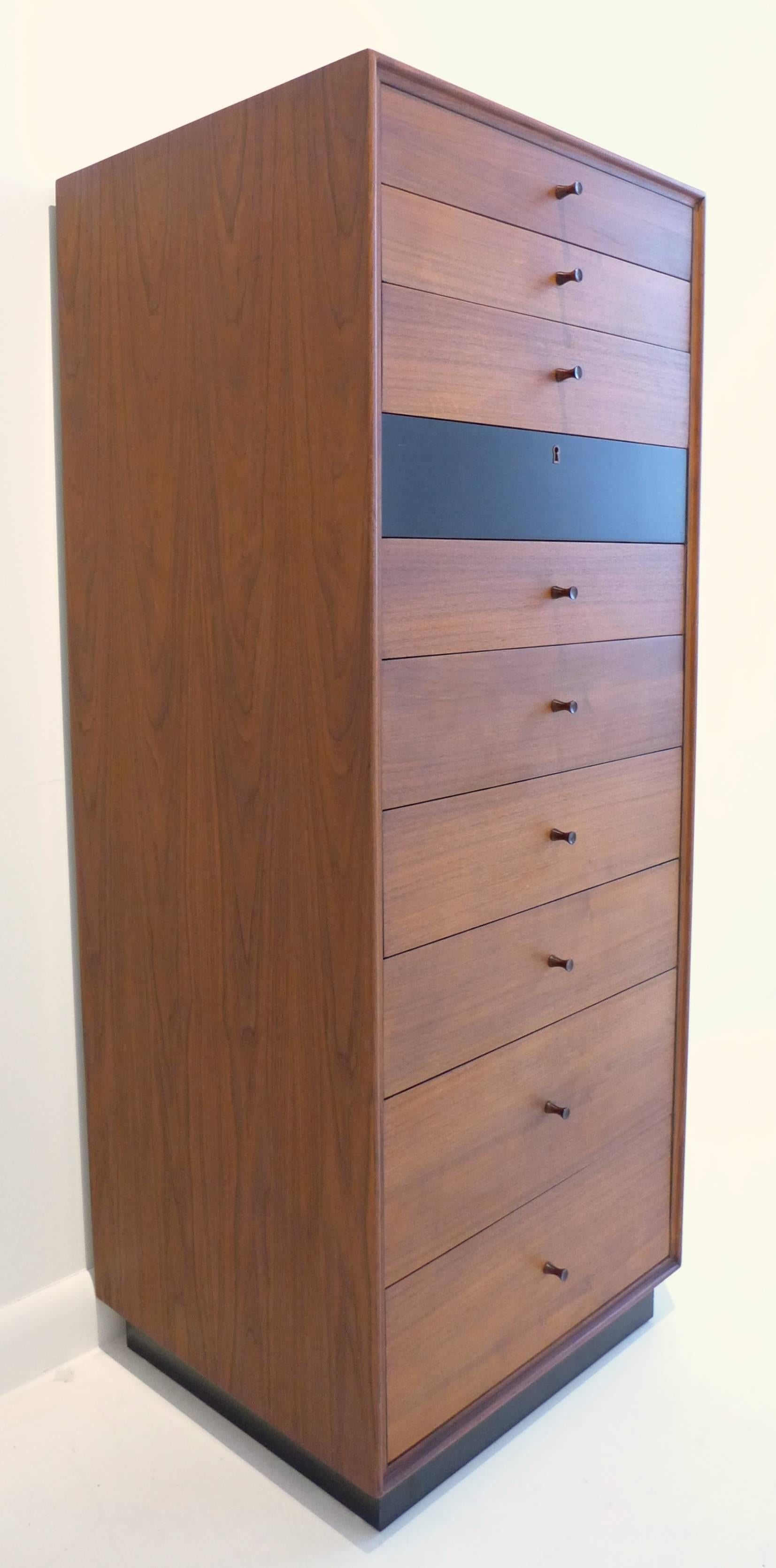 Beautifully proportioned ten-drawer chest with graduated drawers and a recessed plinth base. Of walnut and black lacquered wood with hourglass rosewood pulls. The lacquered drawer adds graphic punch and is keyed. Designed as a lingerie chest by Kipp