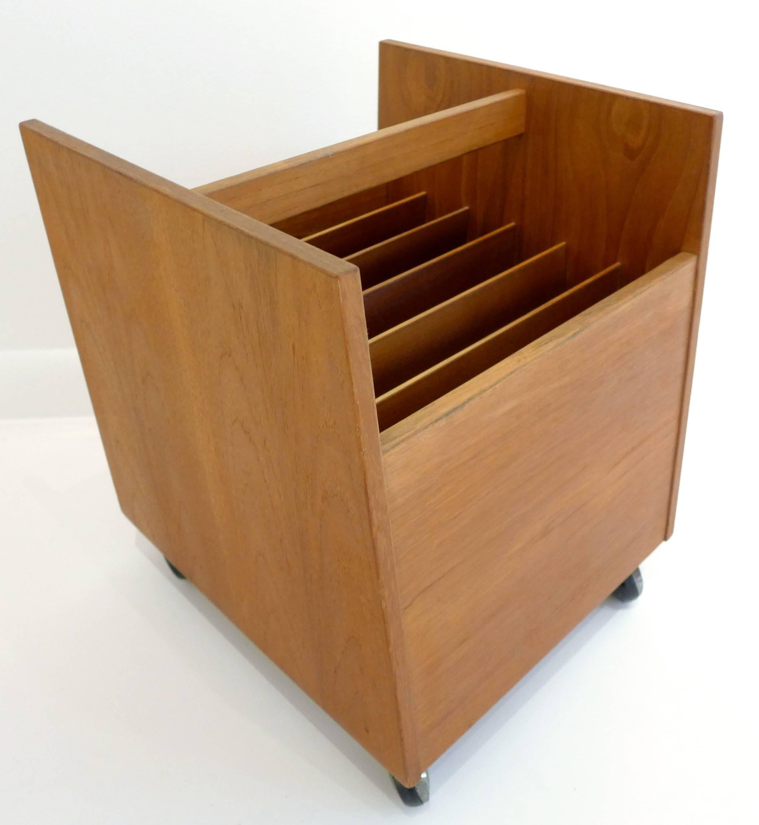 Teak-veneered magazine or record bin with vertical dividers, on casters. Designed by Rolf Hesland for Bruksbo, Norway, circa 1960s. Retains original label.