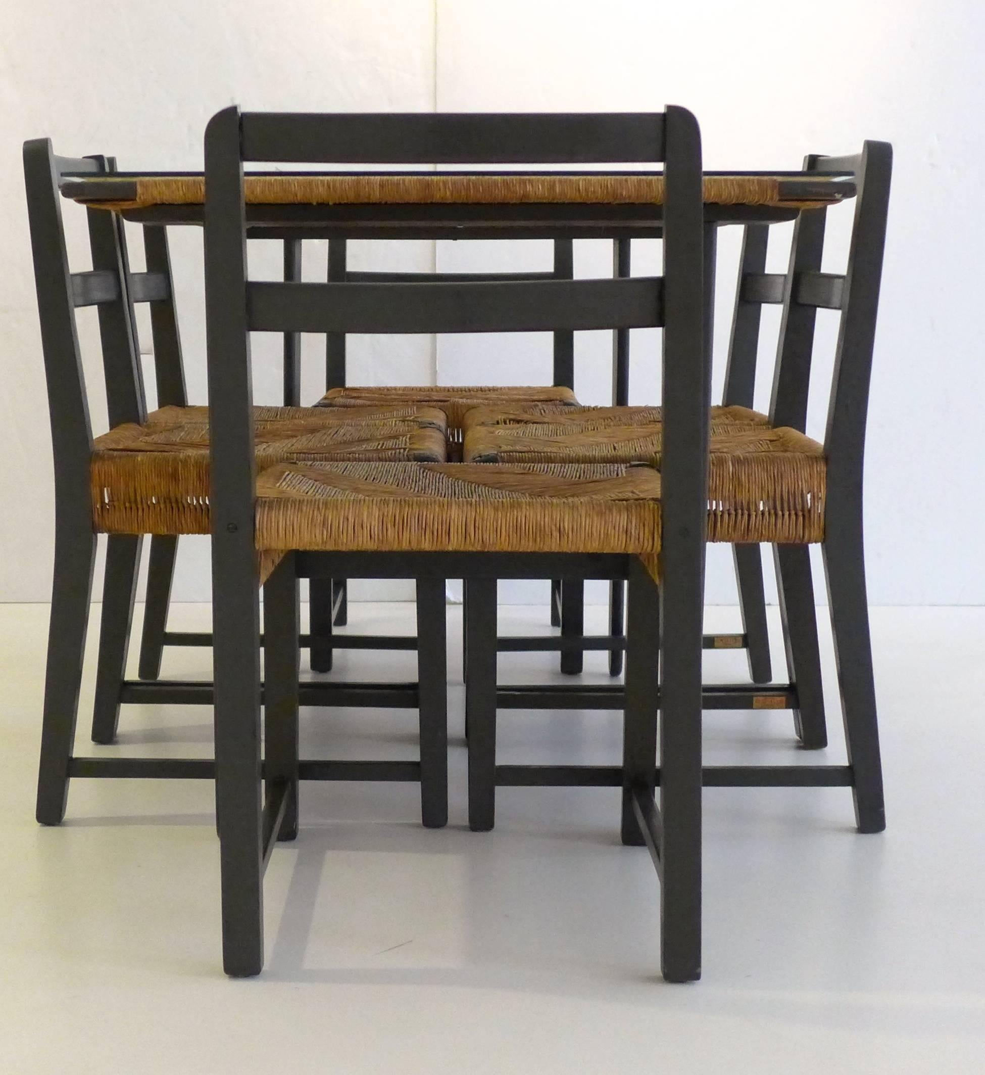 Dining table with six chairs, of painted pine with woven fiber cord. The table top features an open central section surrounded by fiber cord, under a glass panel. The chairs fit tightly within the frame of the table. Designed by Michael van Beuren