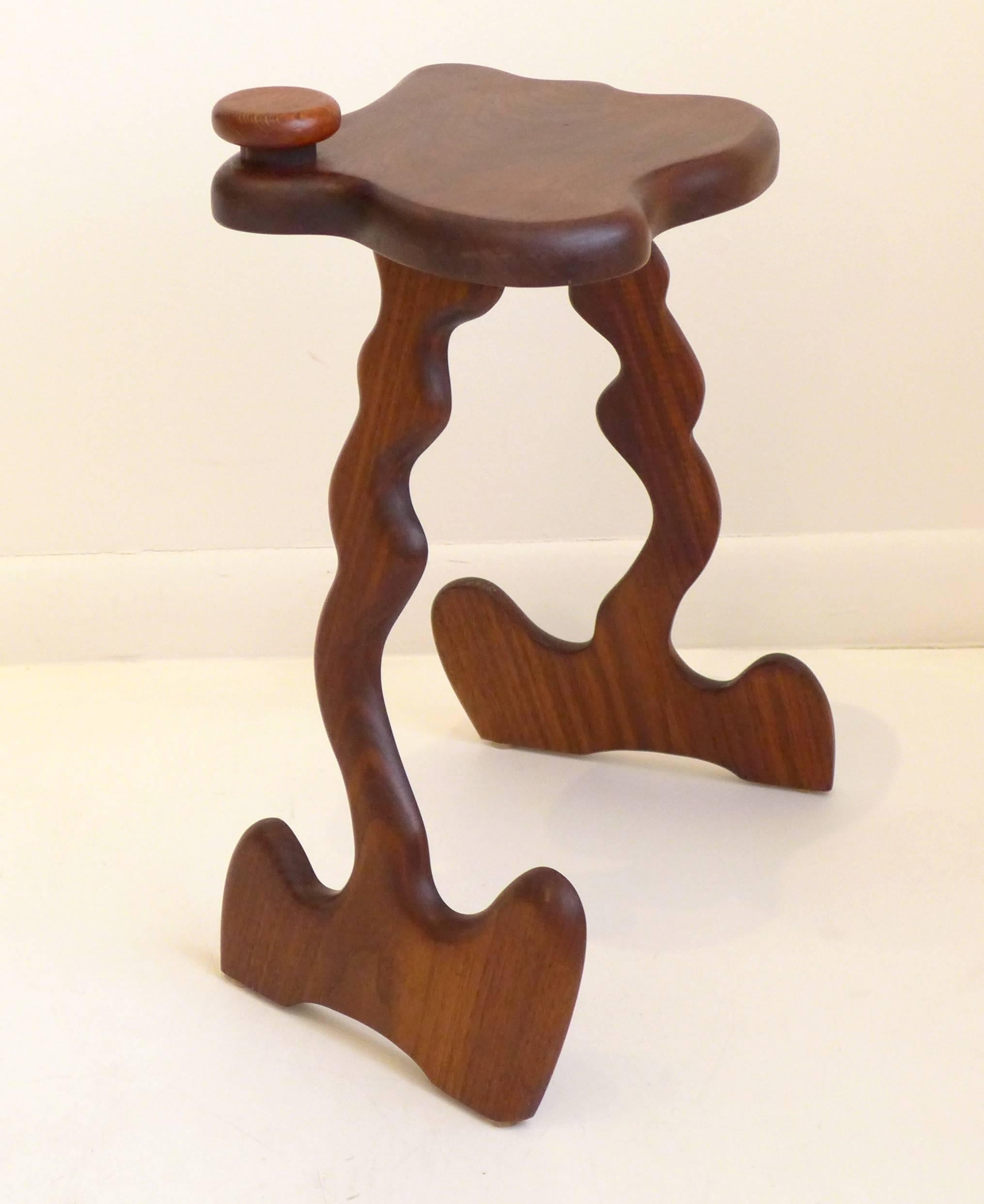 Fanciful and anthropomorphic side table (or drink stand) in walnut with a free-edge top and biomorphic legs and feet--sort of Gaudi by way of Wendell Castle, with an interesting play of positive and negative space to the base. By New York architect,