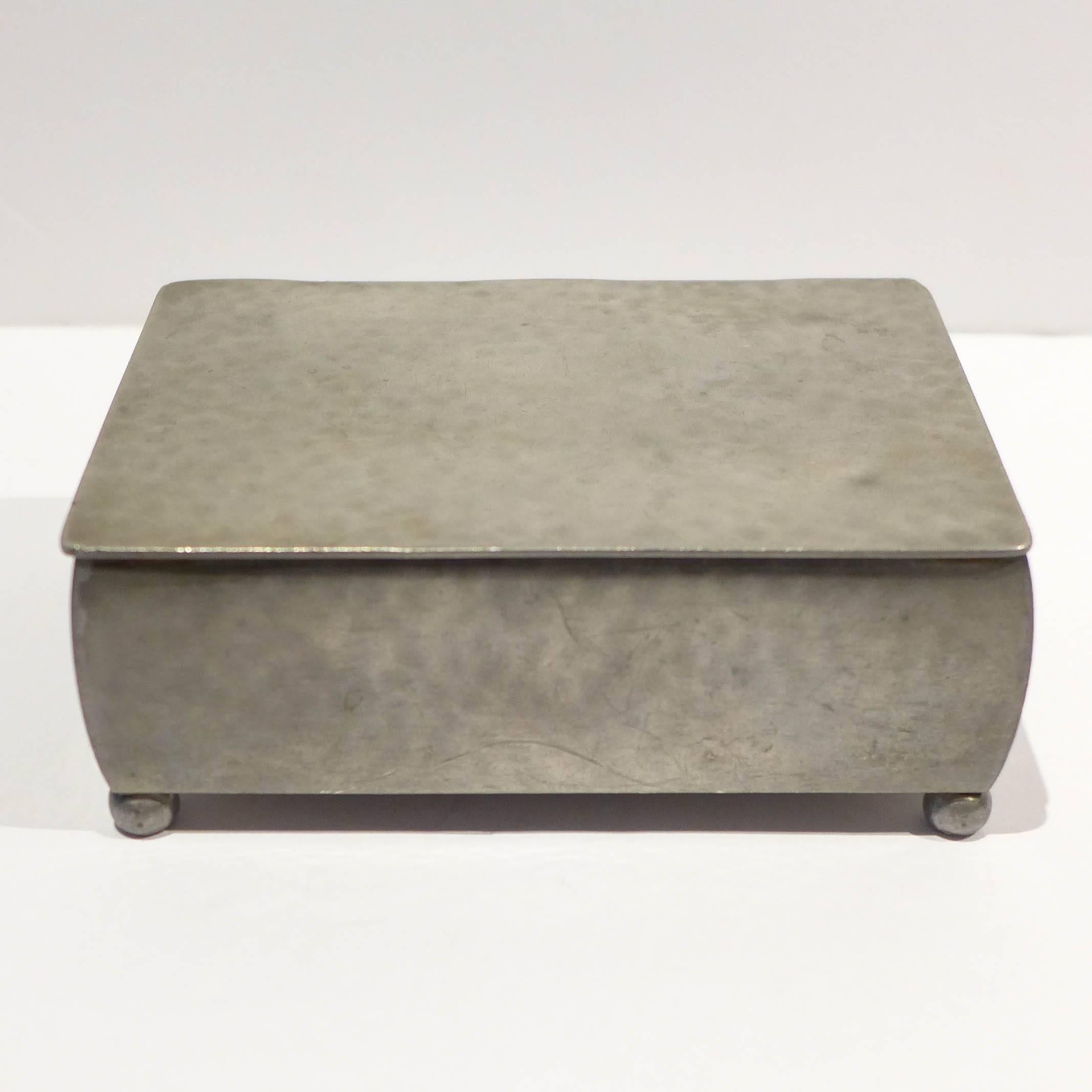 Hand-forged, footed box of hammered pewter with hinged lid and birchwood lining. A sleek casket form adorned only by the Hammer texturing. Designed by Just Andersen for his own company. An early work by this Danish master. Full marks on bottom,