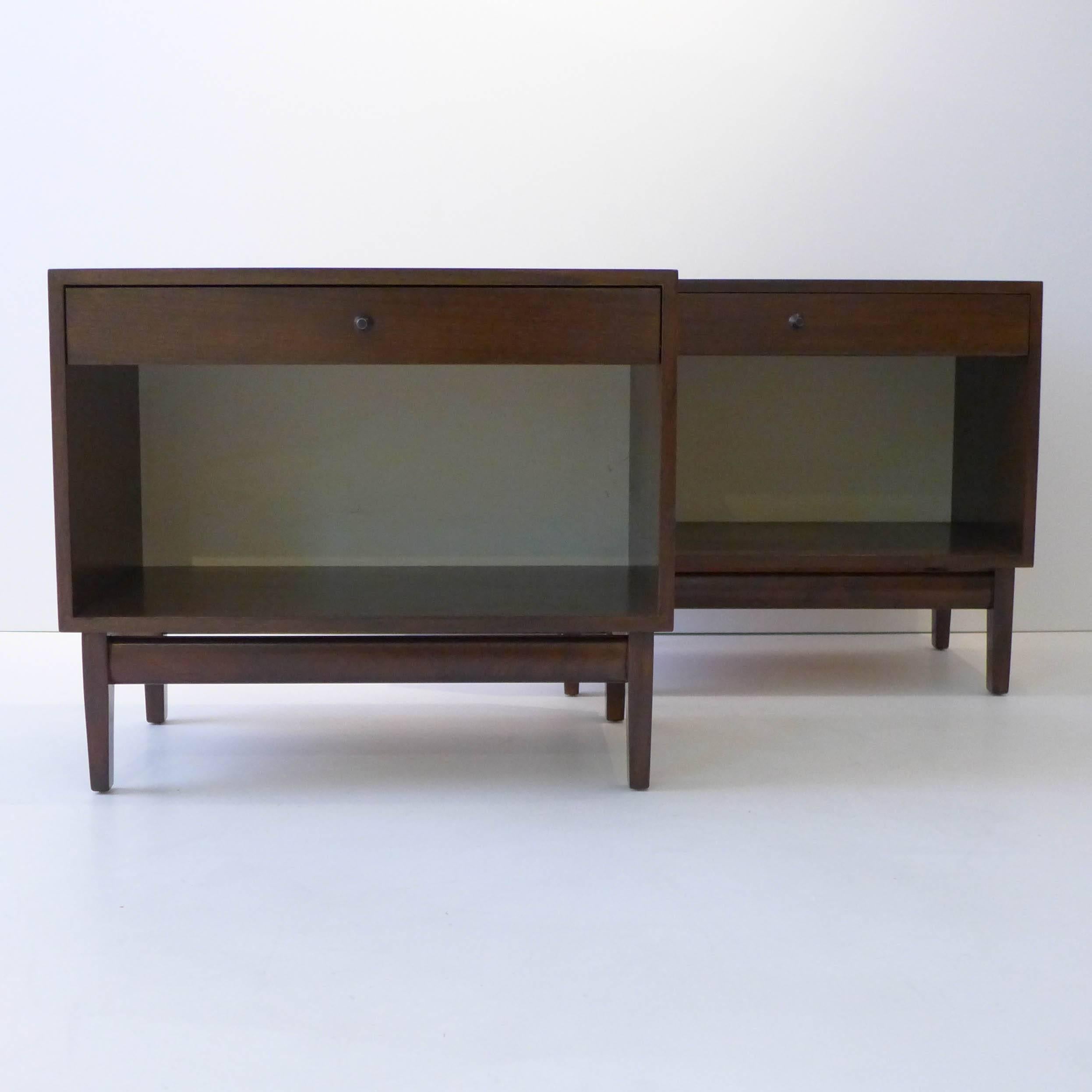 Pair of nightstands of walnut with white Micarta rear panels and painted metal pulls. Designed most likely by Kipp Stewart as part of his American Design Foundation line for Calvin Furniture, circa 1950s. With the original metal tag.