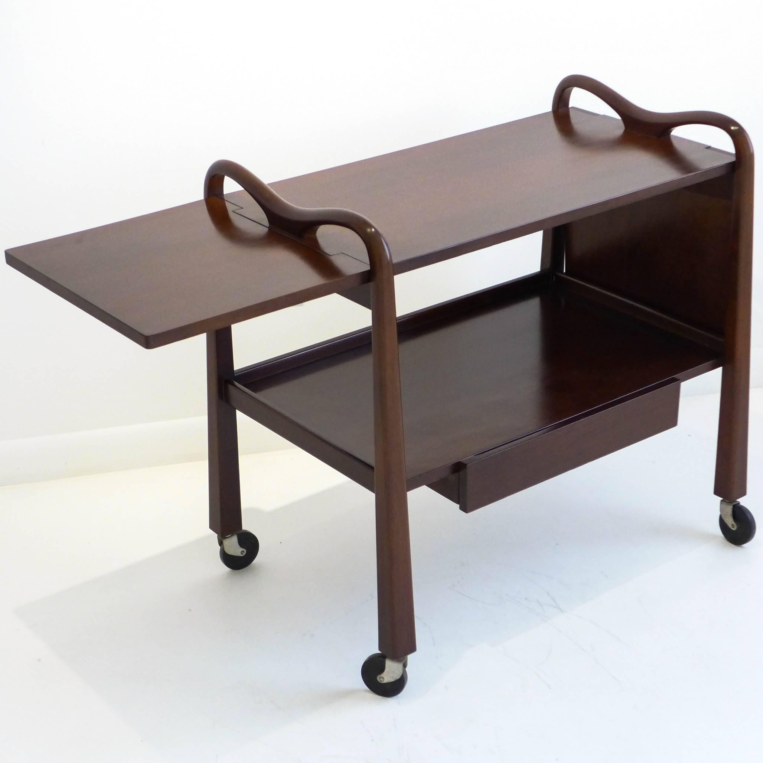 Rare rolling bar or serving cart of Cuban mahogany with integrated handles, flaring legs, a medial drawer and sides panels that can be raised or lowered. An elegant design by American designer Edmond J. Spence, produced in Mexico by Industria