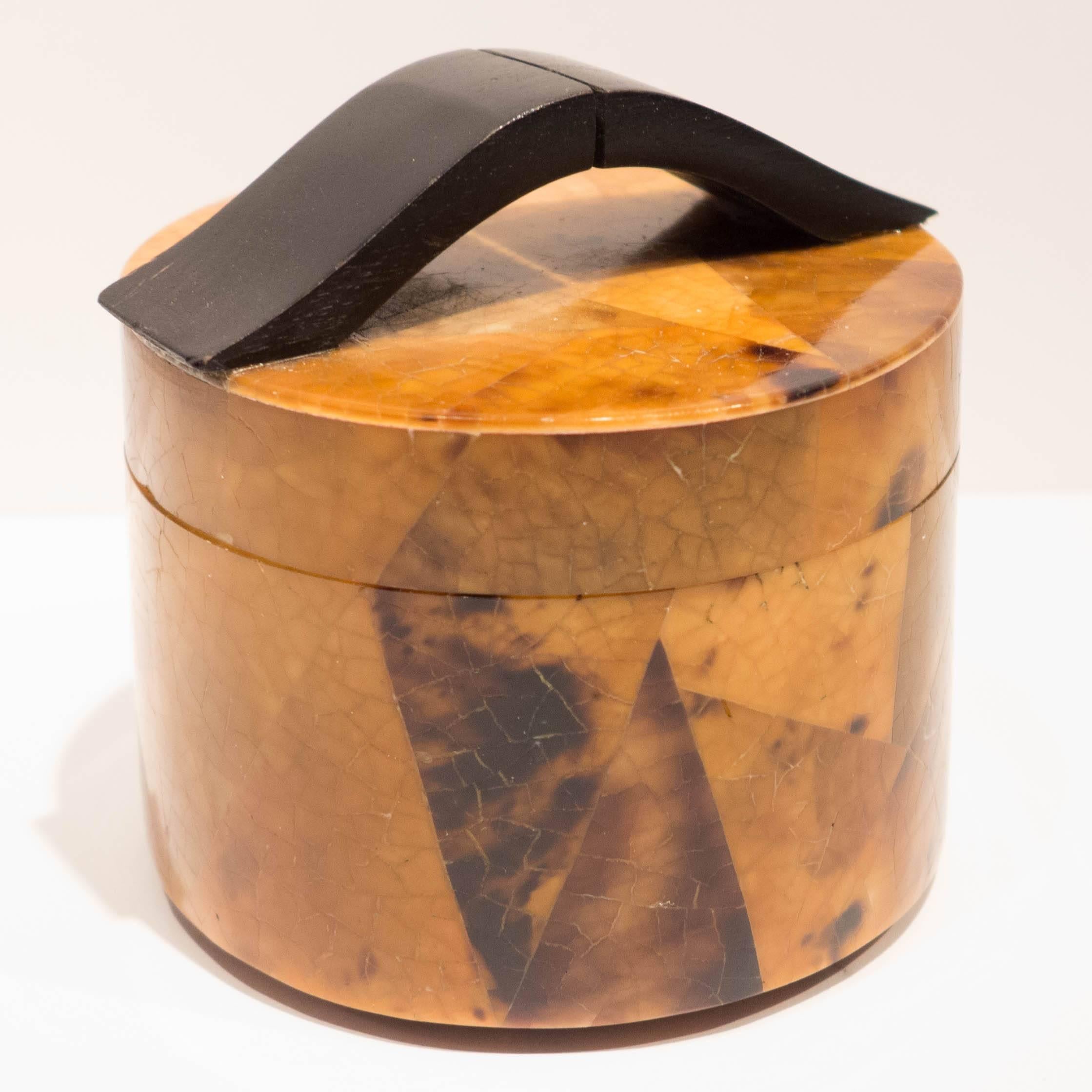 Small round box with curved wooden handles and a crushed shell veneer over mahogany. With an abstract deco pattern. By Ria And Yiouri Augousti of Paris, circa 1980s. Stamped on leather lining underneath.