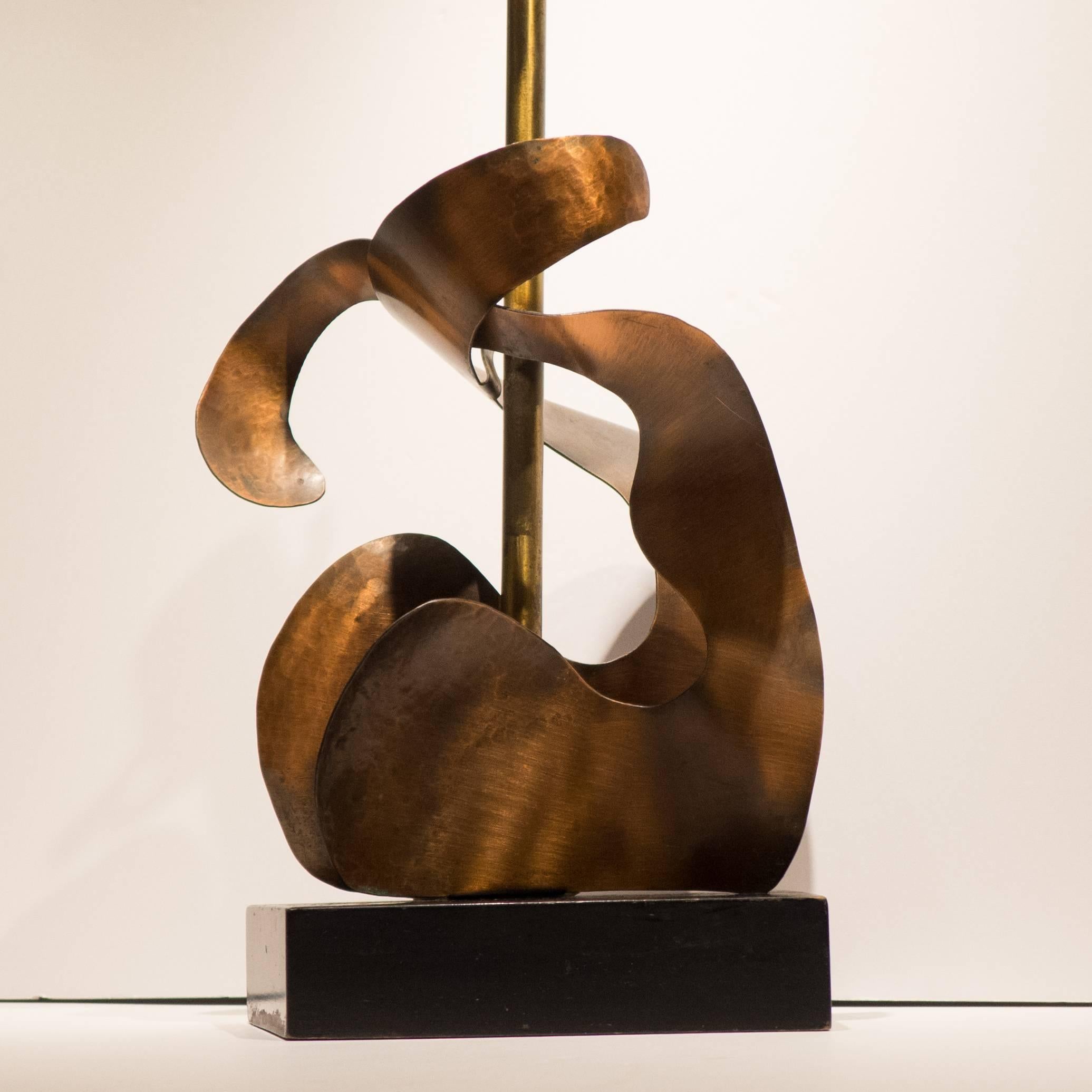 Abstract figural lamp of cut and hammered copper with a brass stem and ebonized trapezoidal wood base. Made by Heifetz, circa 1952.  Incised signature to base.  Retains original wiring which needs to be replaced, along with a harp and shade. 