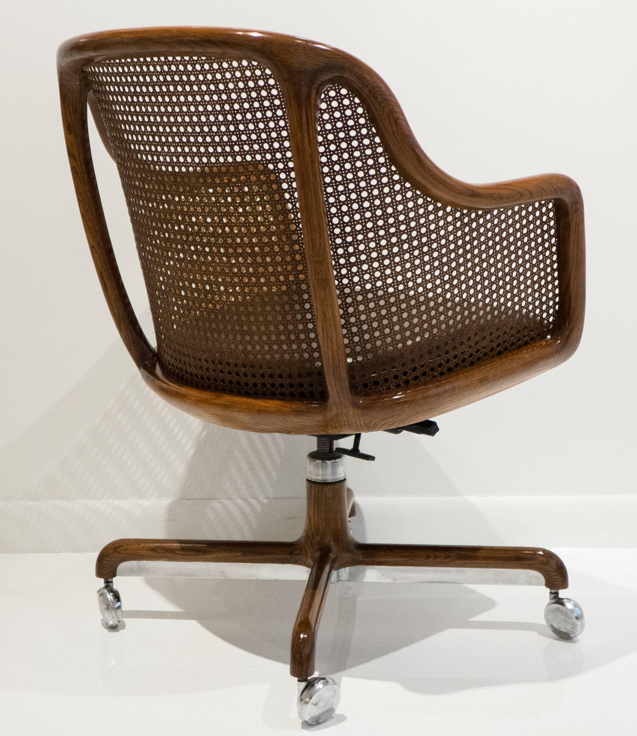 Adjustable tilt-back armchair with sinuous solid oak frame, caned back and leather seat. Designed by Ward Bennett and produced by Brickel Industries, circa 1975.