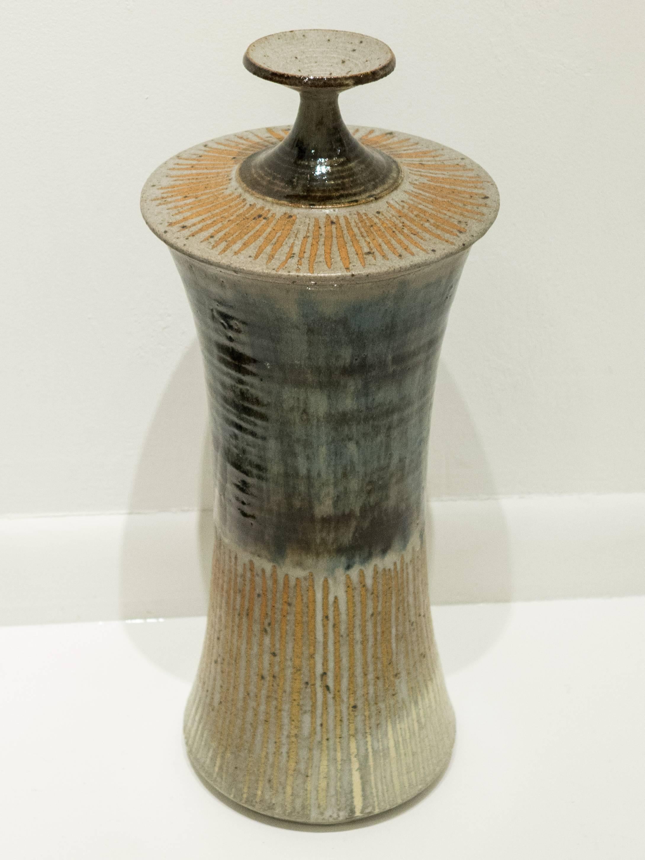 Tall lidded vessel by New Hampshire master potter Gerry Williams, featuring a painterly application of glazed and unglazed elements, and semi-gloss and matte glazes. Executed circa 1970s. Incised signature and cypher.