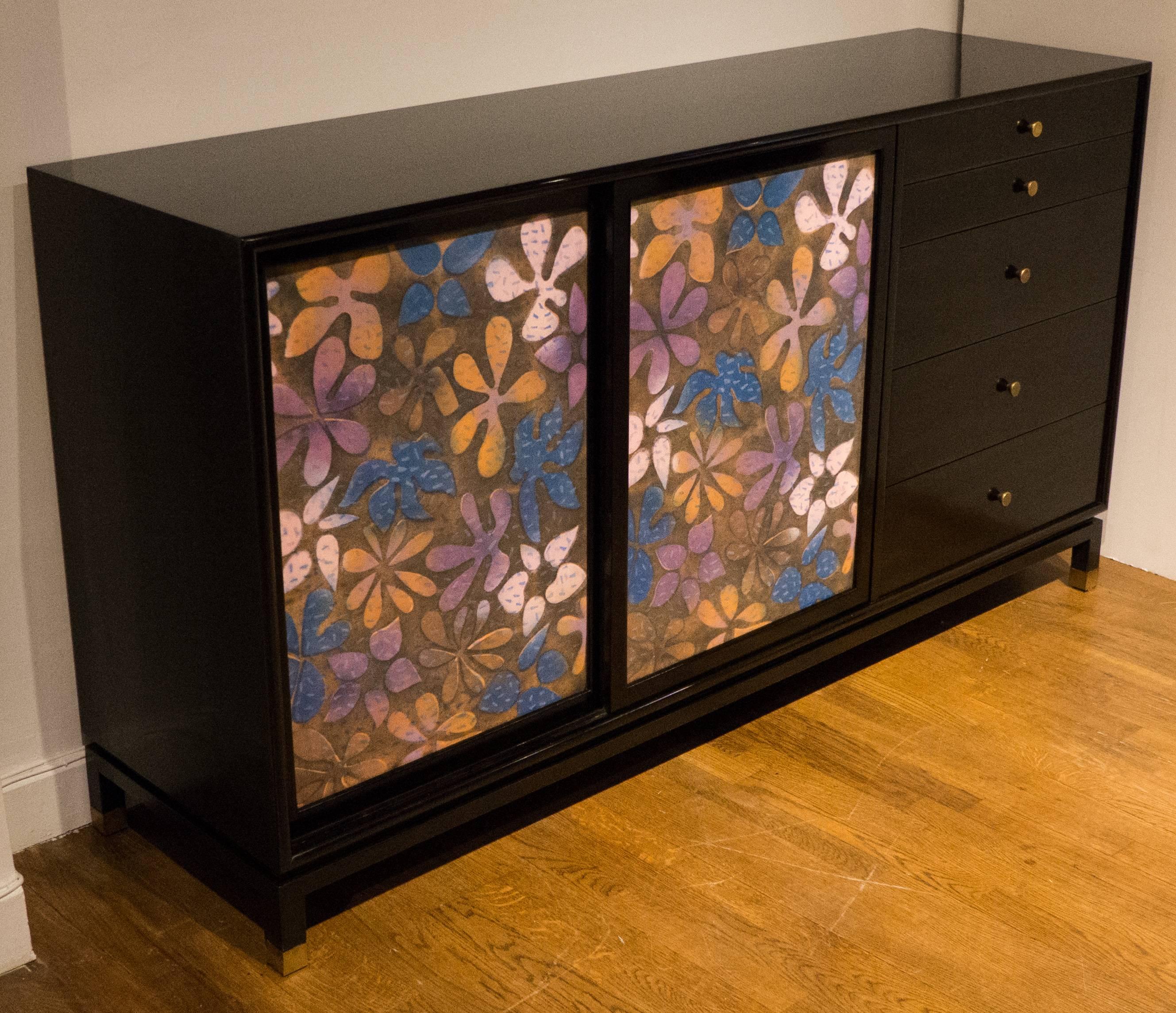 Cabinet or dresser featuring inset high-fired enamel-on-copper doors with a richly colored floral decorative motif. Dark mahogany case with brass pulls and sabots; white-lacquered interior drawer fronts and a finished, white lacquered back. Solid