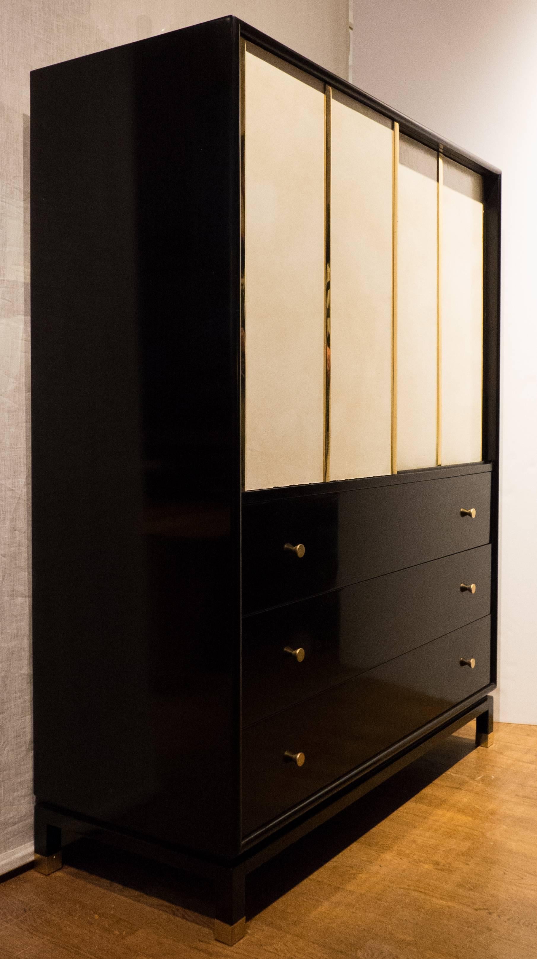 Cabinet in dark mahogany with brass accents, pulls, and sabots, and sliding doors wrapped in original off-white leather. The top section has pull-out storage 
bins; there are four drawers underneath. With solid secondary woods, dovetail