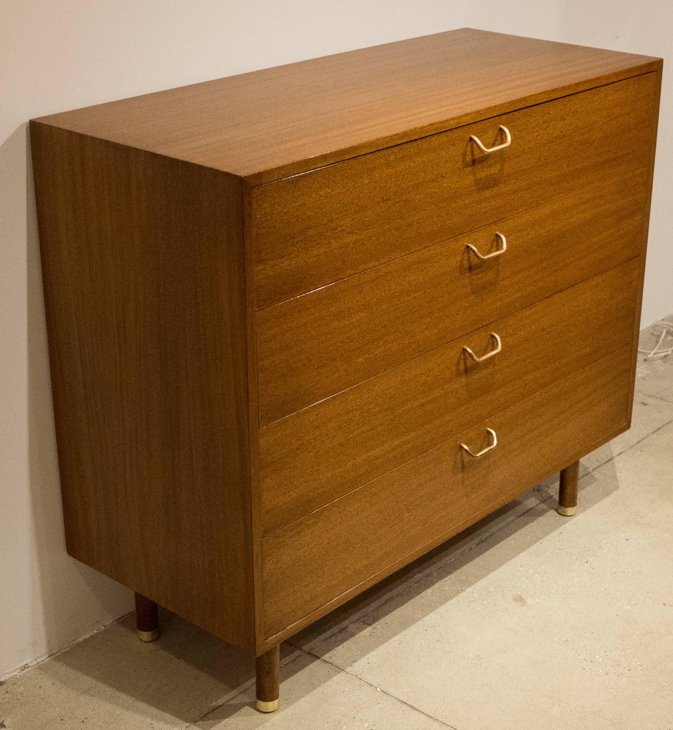 Four-drawer chest of drawers in bleached mahogany with cylindrical wooden legs and brass pulls and sabots. With solid oak secondary woods, dovetail-joined drawers, and a finished, white lacquered rear panel. Designed and produced by Harvey Probber,