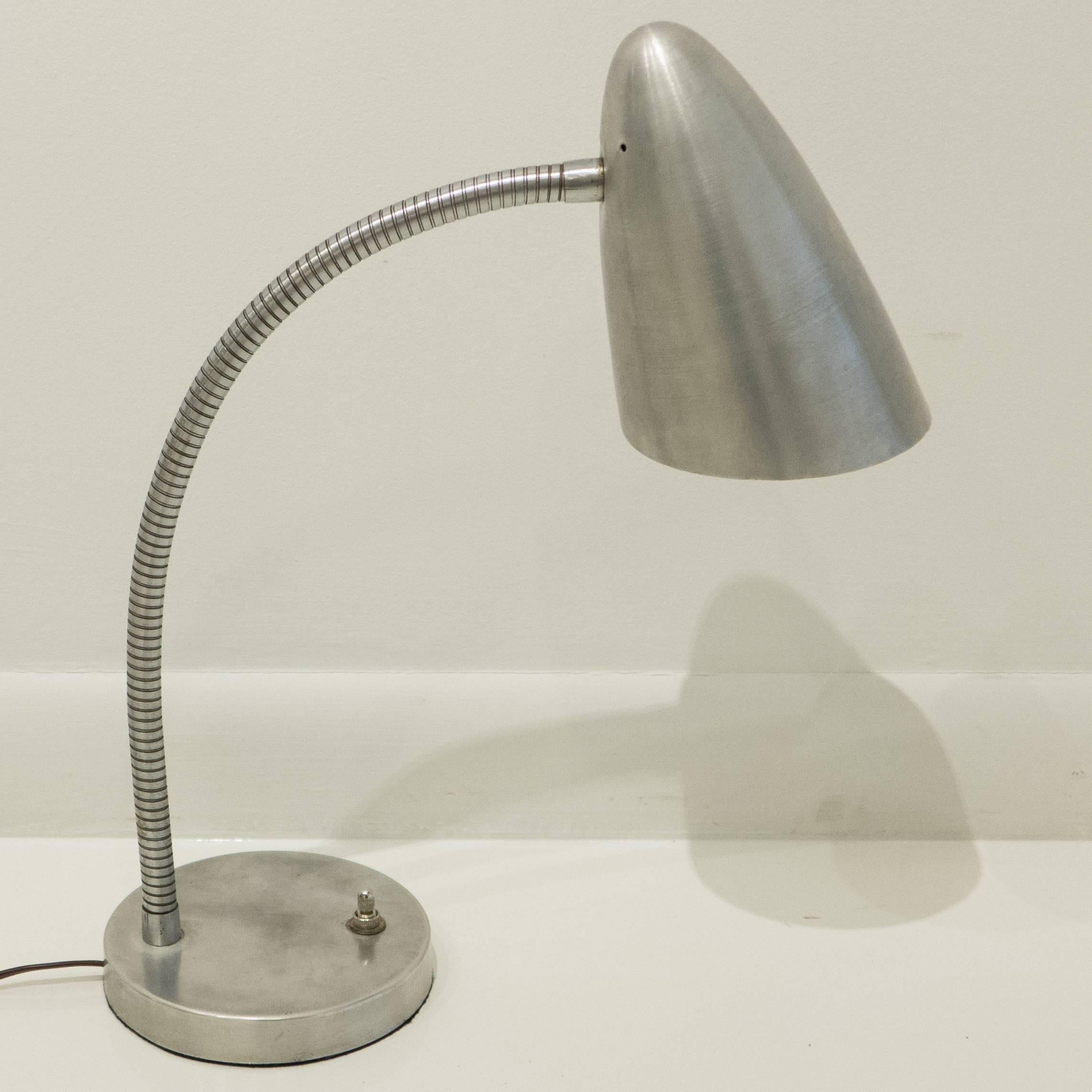 Flexible gooseneck table lamp with a spun aluminum reflector, satin chrome gooseneck, and cast aluminum base, designed by Harry Handler for General Lighting Co, produced circa 1947. An early postwar modernist lighting design that made its way into