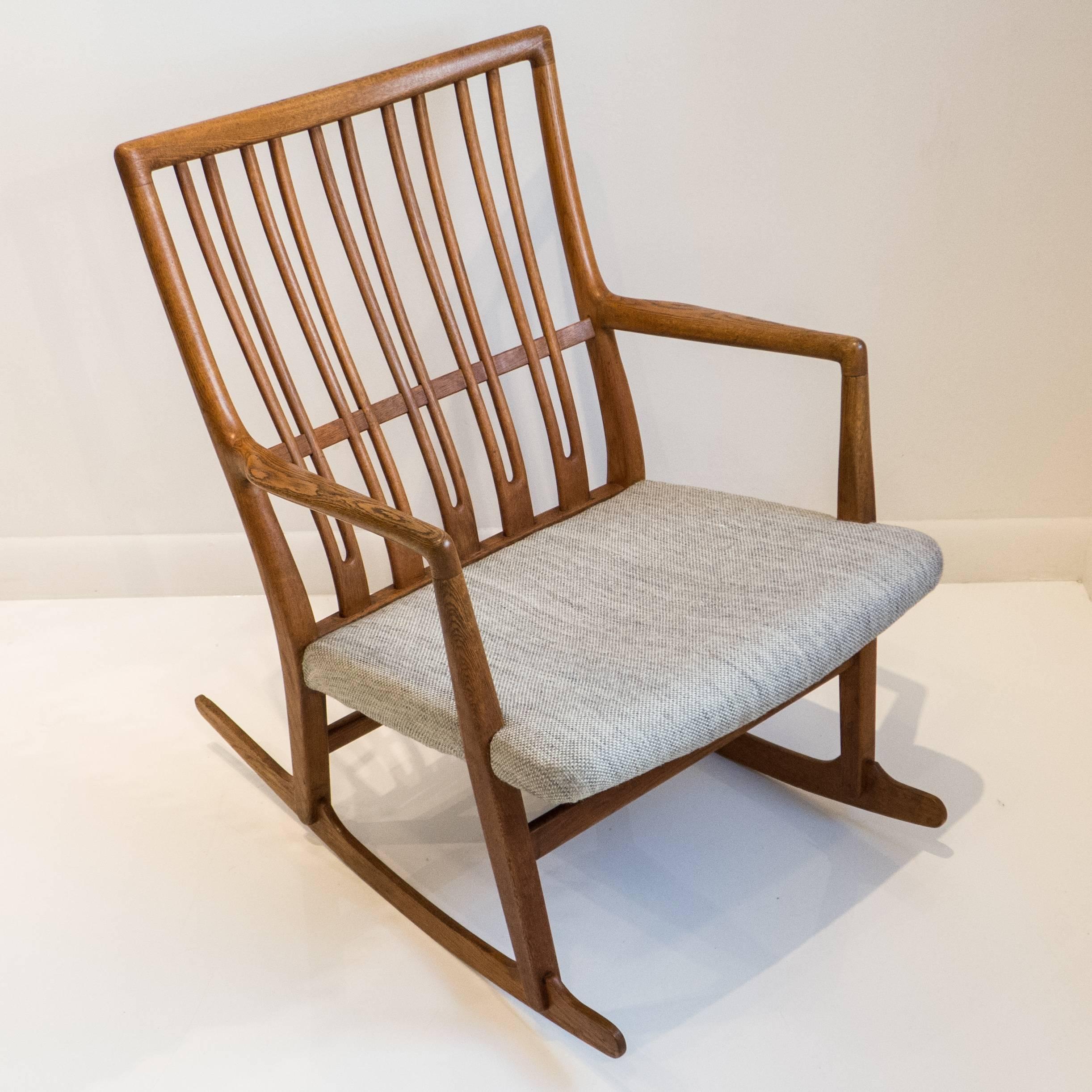 Oak rocking chair with vintage but not original wool fabric seat. An early (1942) Hans Wegner design produced by Mikael Laursen, circa 1960s. Note: Often attributed online to a 1940s production date, the rocker was still in the Illums Bolighus