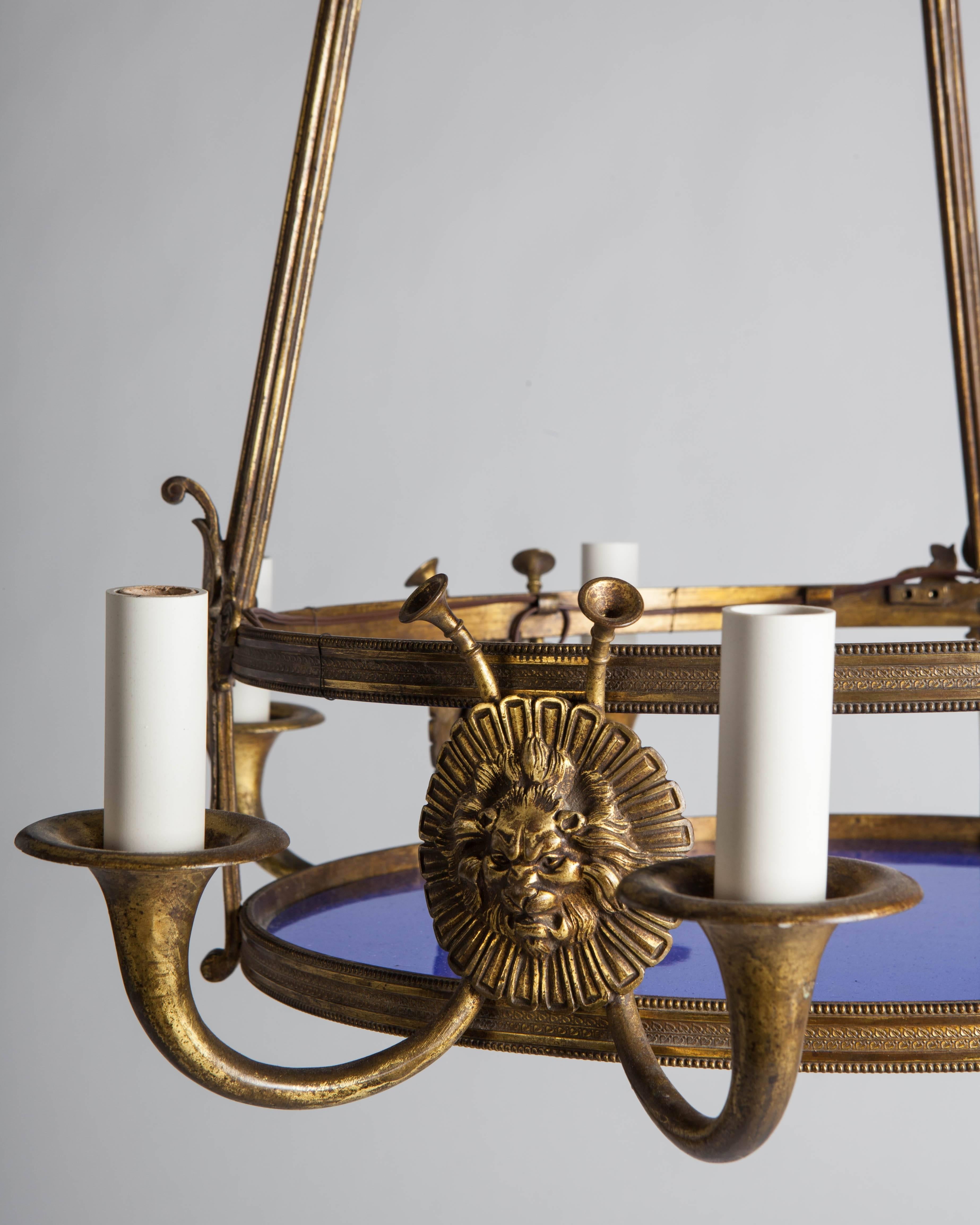 AHL3927

An antique bronze chandelier having a cobalt blue lens. Three pairs of arms issue from behind lion masks. The whole in its original worn gilded brass finish. Due to the antique nature of this fixture, there may be some nicks or