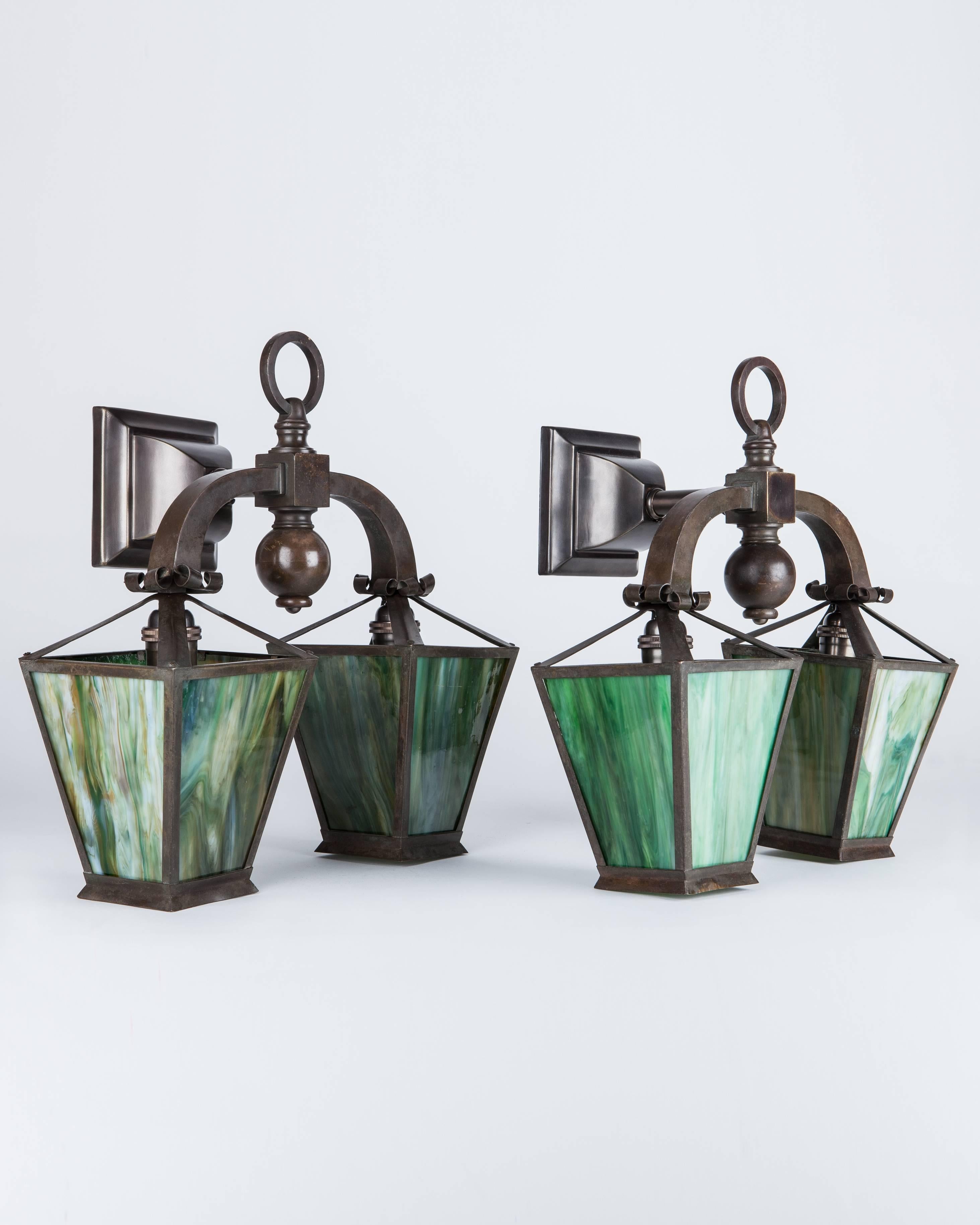 AIS2944
A pair of antique Arts and Crafts period double-light sconces, with tapered four-sided lantern shades in striking green art glass. The metalwork all in age-darkened brass. Originally fitted for both gas and electric. Due to the antique