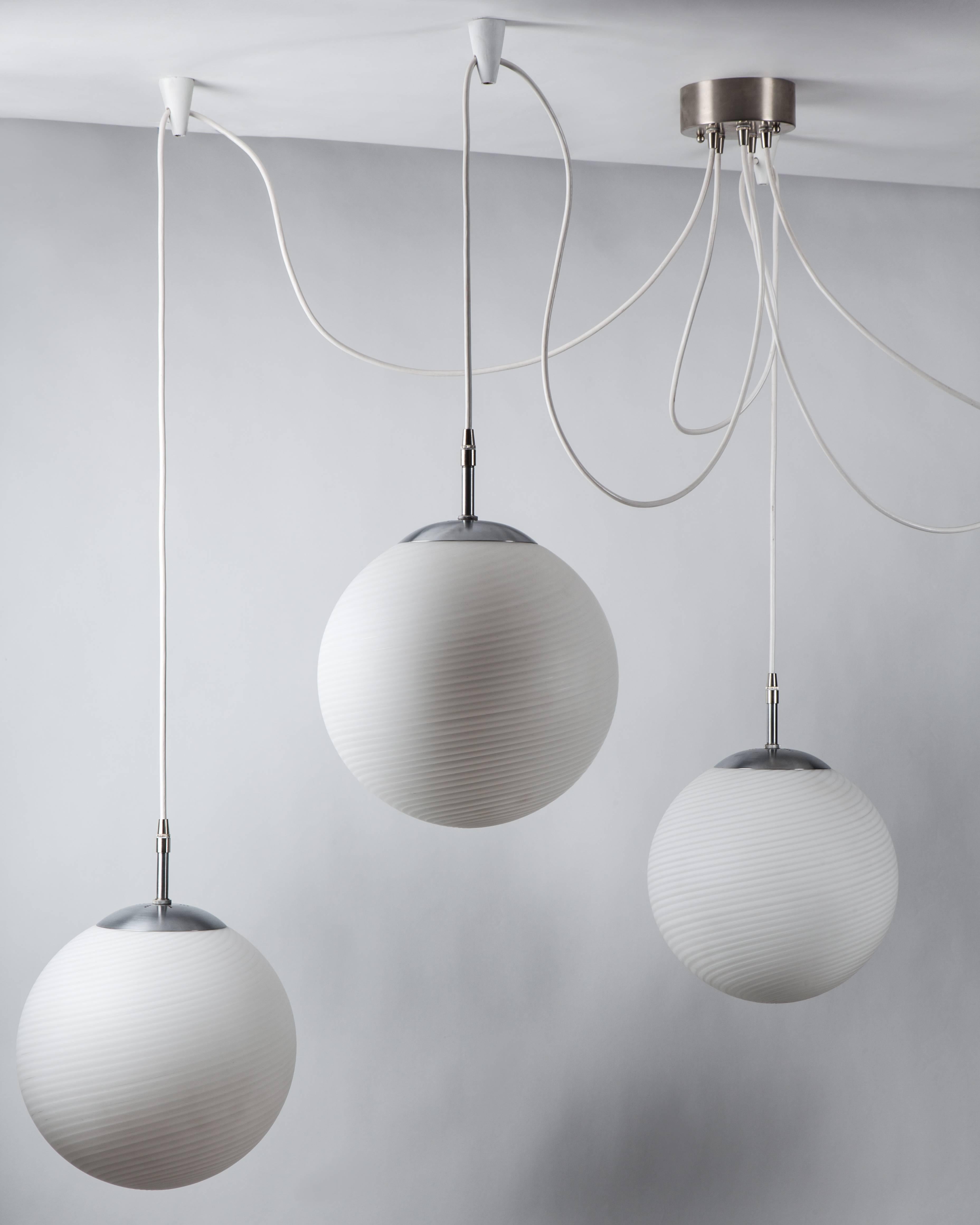 AHL3906.
A five-light fixture of swirled glass globes suspended from white enameled wooden anchors. Having satined aluminum and nickel metalwork, the fitters are marked with German export stamps; the wood pieces marked 