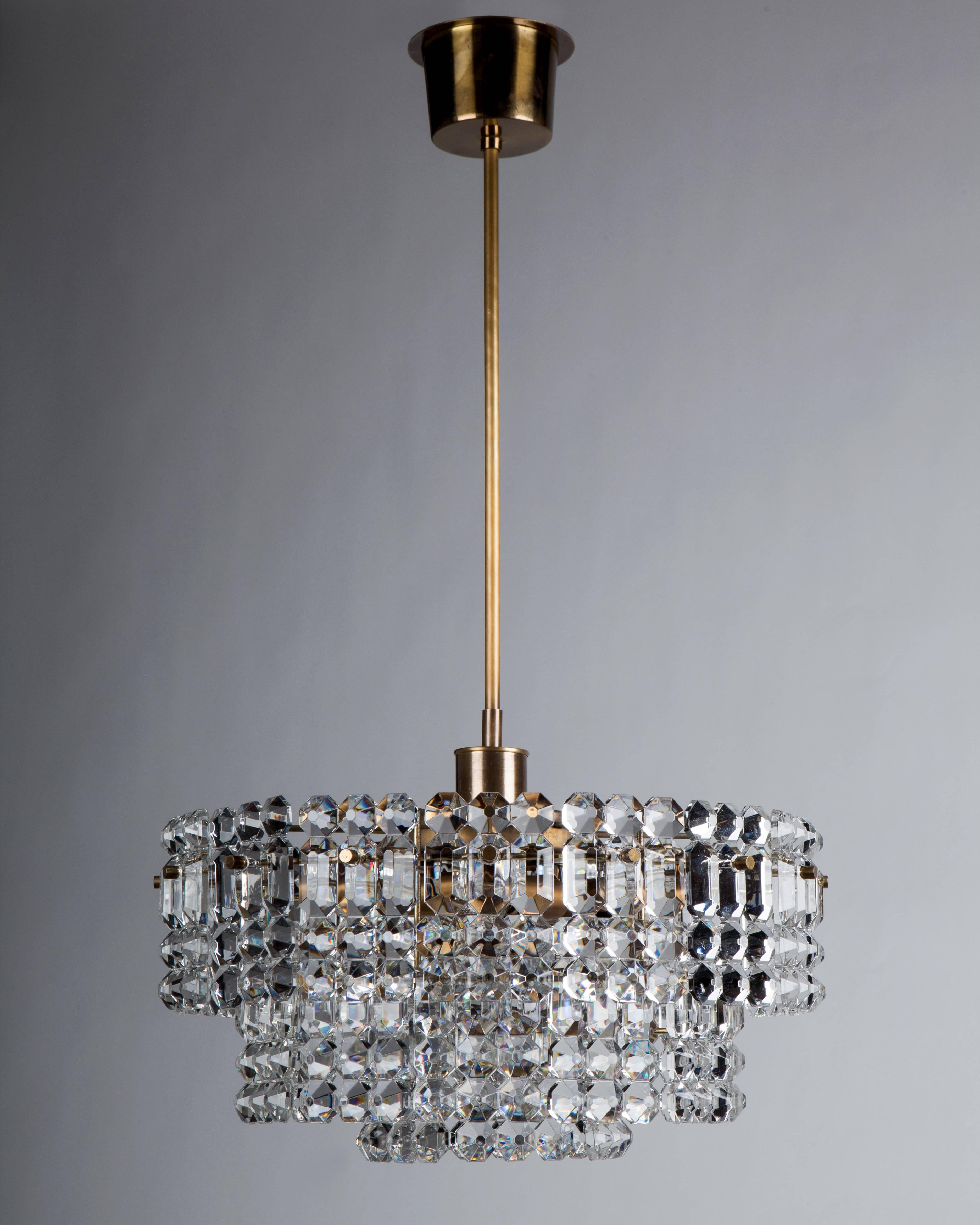 AHL3973.
A three-tier chandelier with tiles of thick clear glass held on a dore brass frame in graduated hoops. This mid century modern fixture is attributed to the Austrian maker Kinkeldey. Due to the antique nature of this fixture, there may be