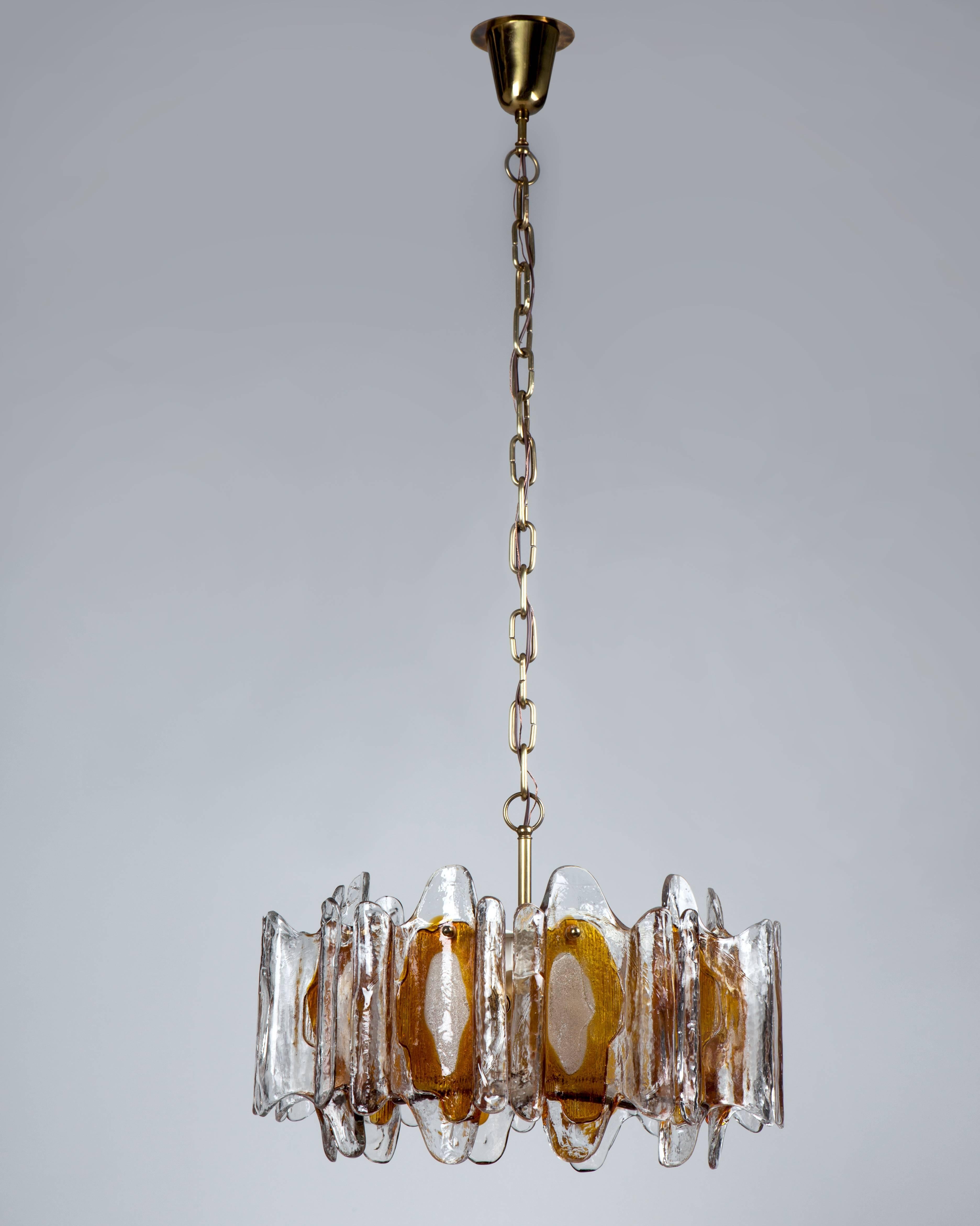 AHL3979.
A vintage orange and clear textured glass chandelier in its original white enamel and brass finish. This mid century modern fixture is attributed to the Swedish glassmaker Kalmar. Due to the antique nature of this fixture, there may be