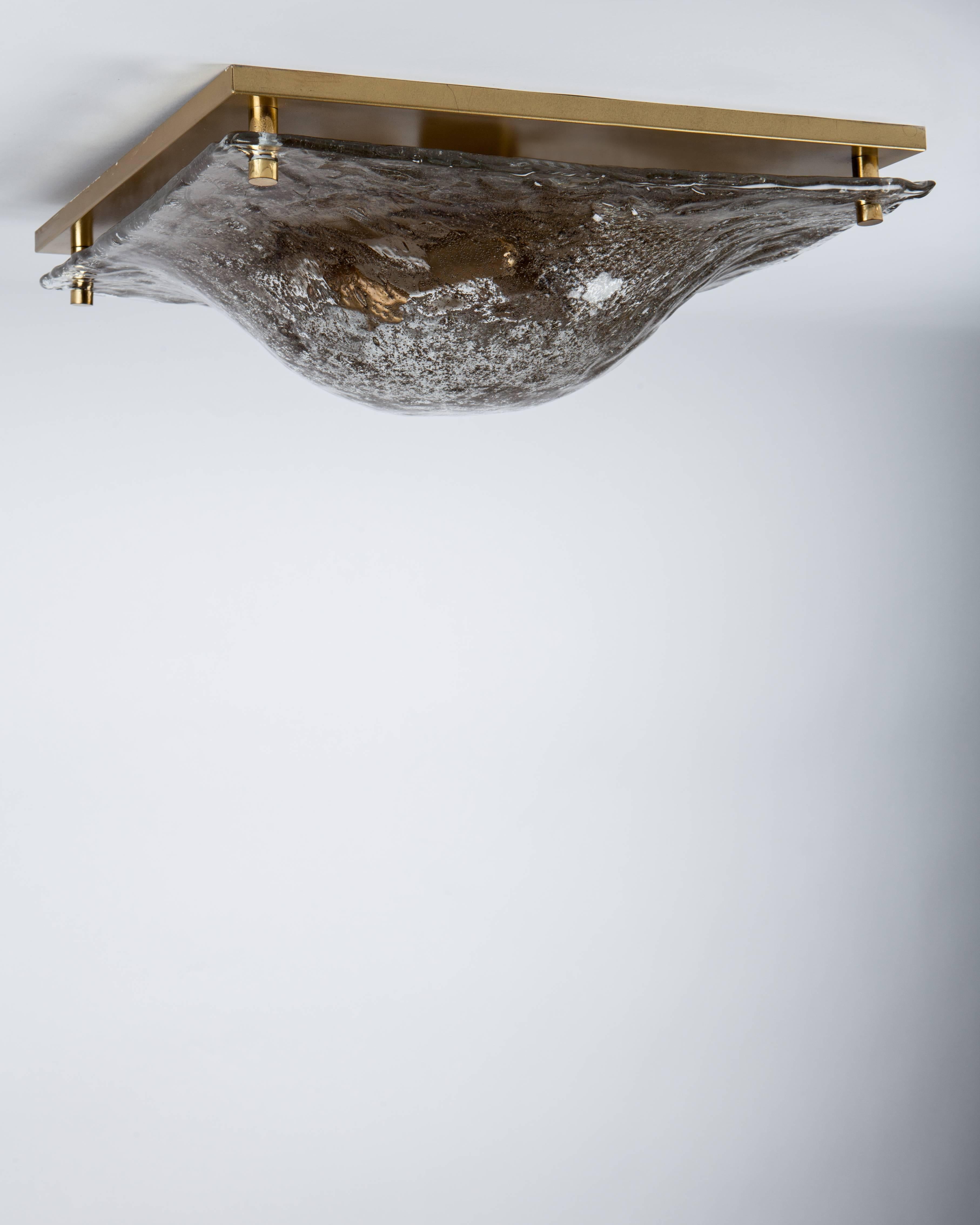 AHL3976.
A large square flush mount with a heavily-seeded and textured clear-to-smoke glass lens and aged brass fittings. This mid century modern fixture is by the German maker Kaiser Leuchten. Due to the antique nature of this fixture, there may